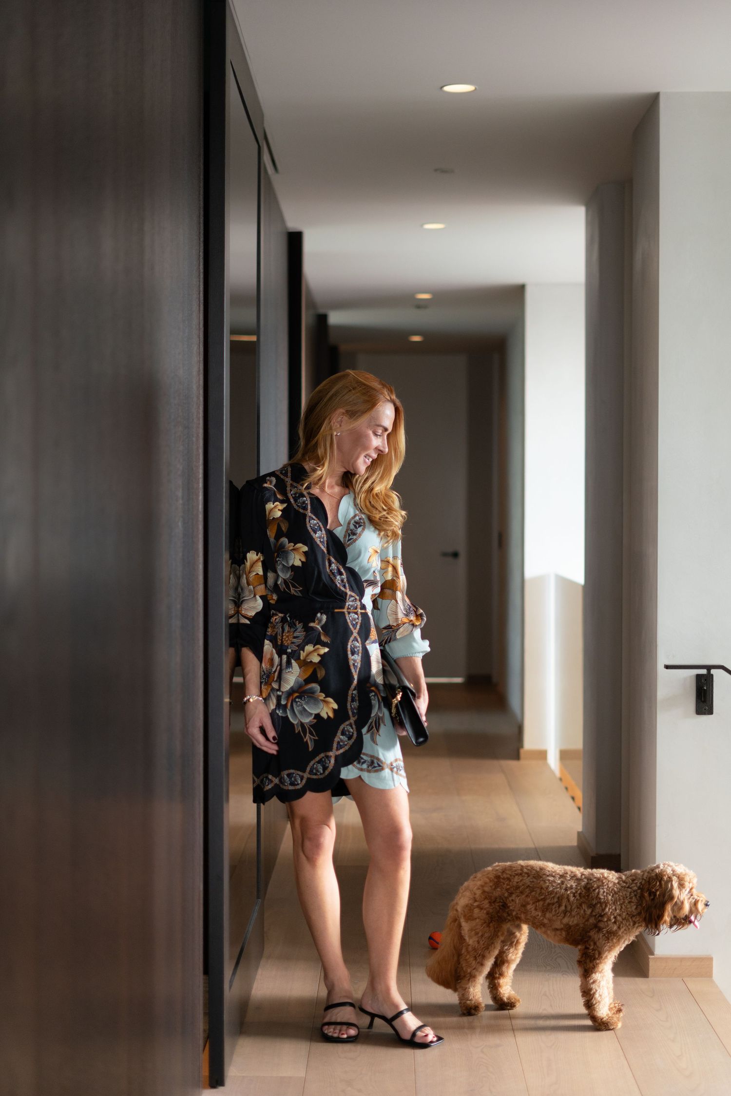 Five sequential photos show a playful interaction between a person in a floral dress and a goldendoodle dog in a hallway.