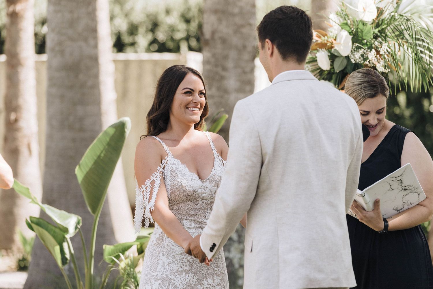 Wedding ceremony celebration in a palm tree garden with elegant white decor.