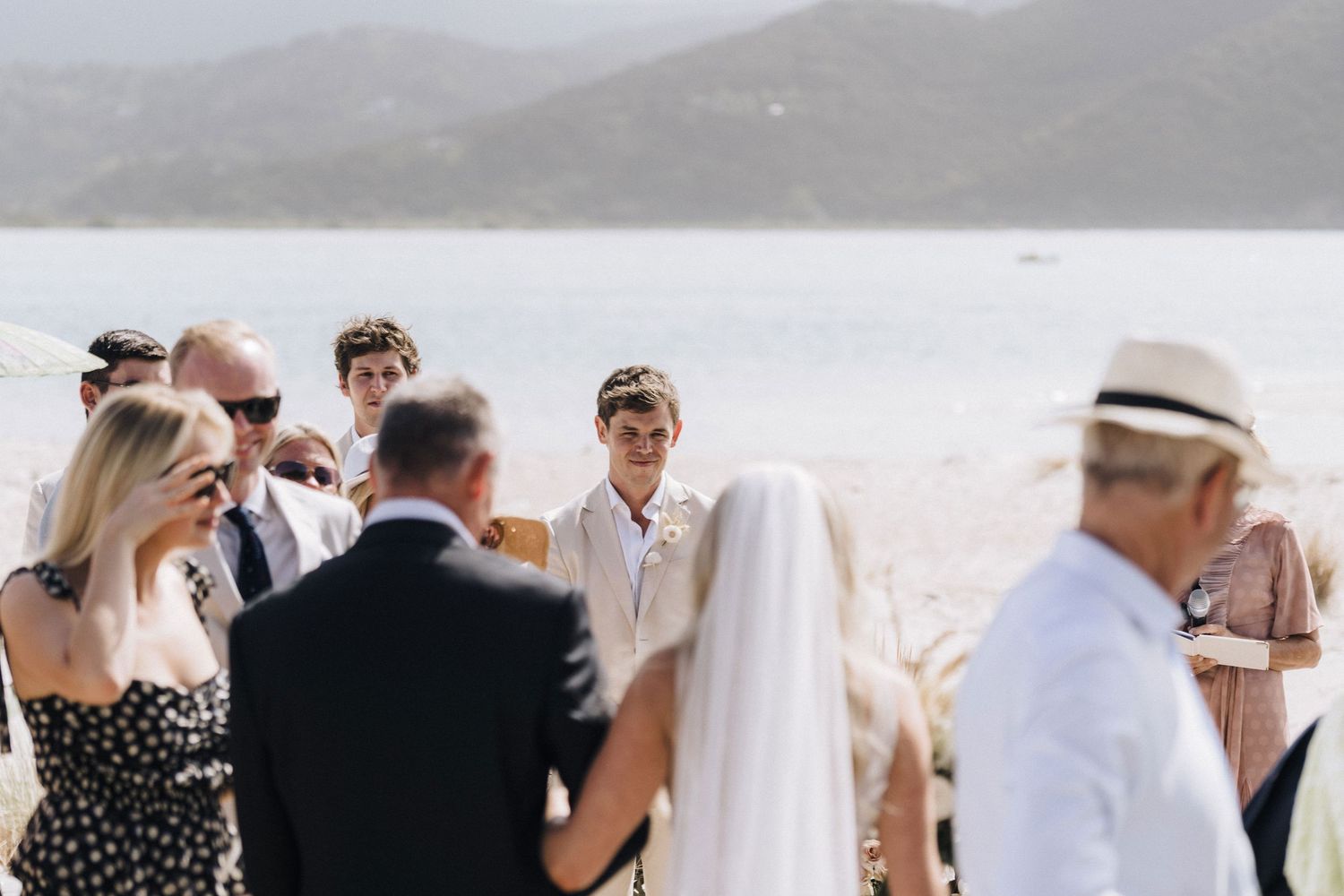 Wedding ceremony taking place by a scenic lake with mountains in the background.