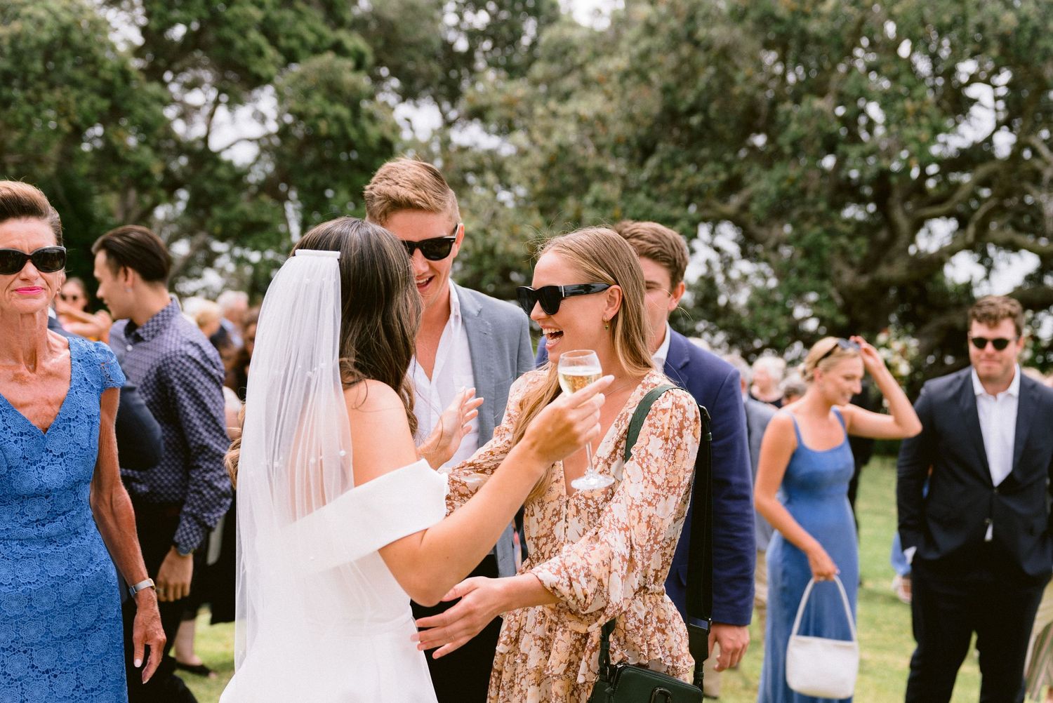 Outdoor wedding reception with guests mingling under bright summer skies.