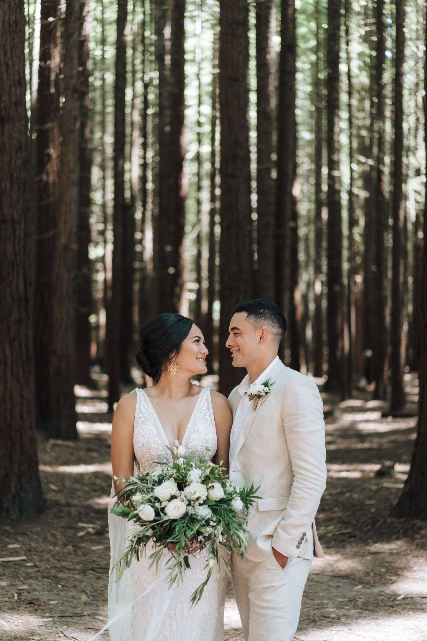Wedding couple shares intimate moments in a serene forest setting filled with tall pine trees.