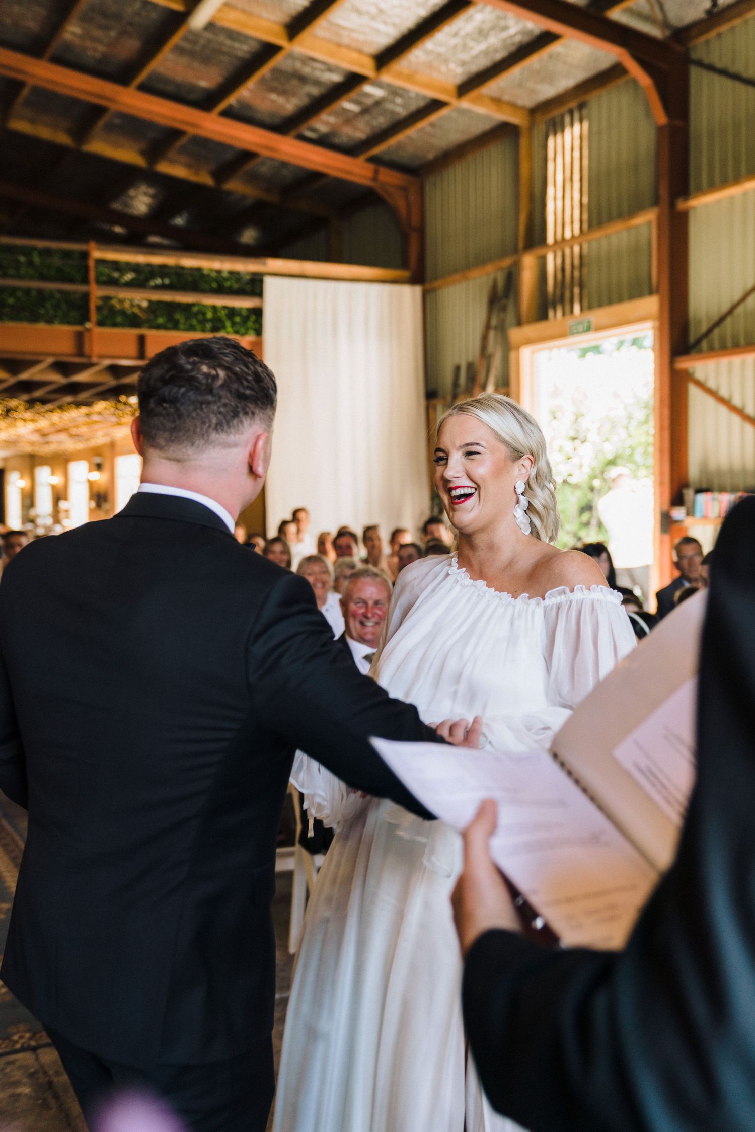 A joyful celebration taking place inside a rustic barn venue during a wedding ceremony.