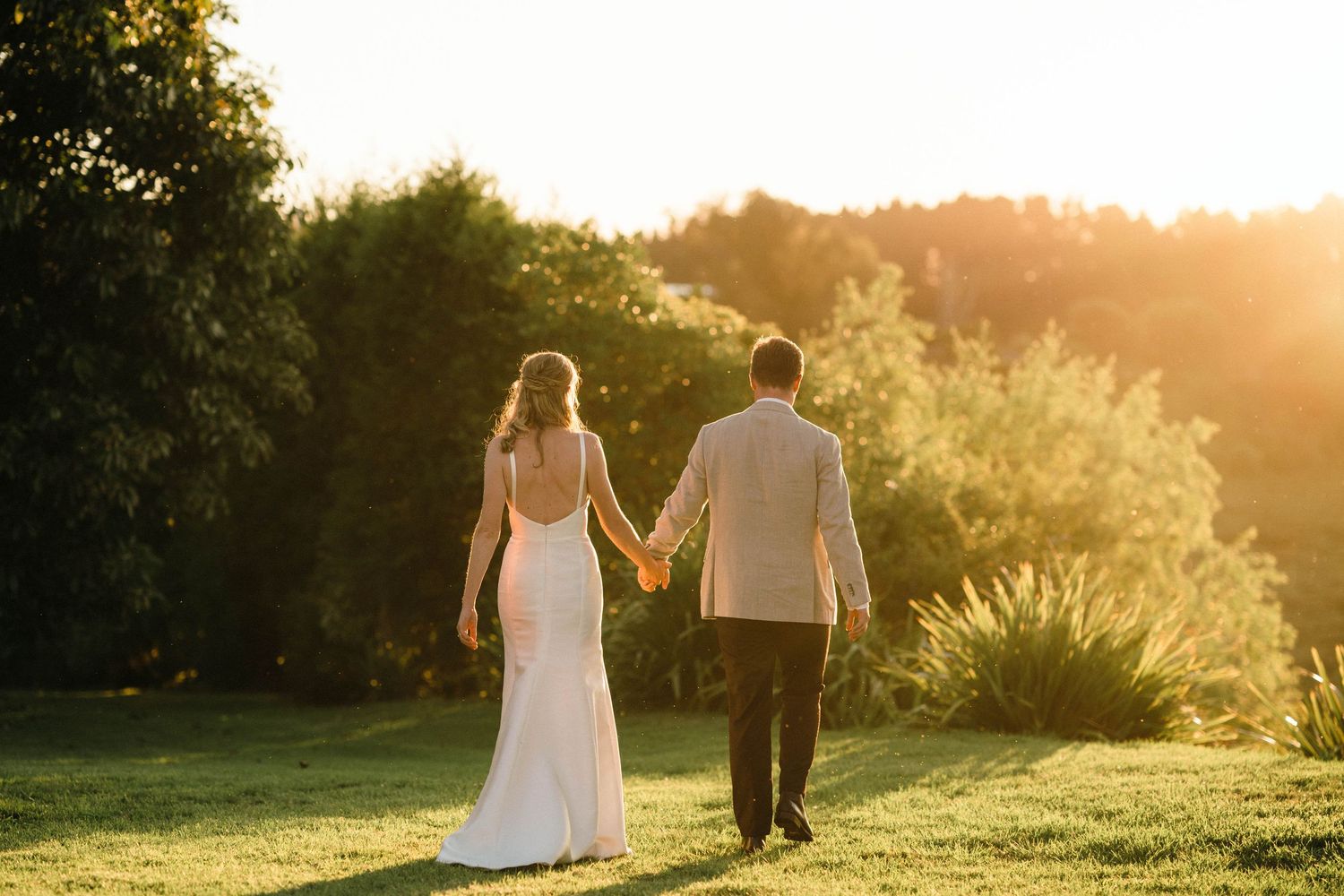 Couple walking through a sunlit garden during golden hour.