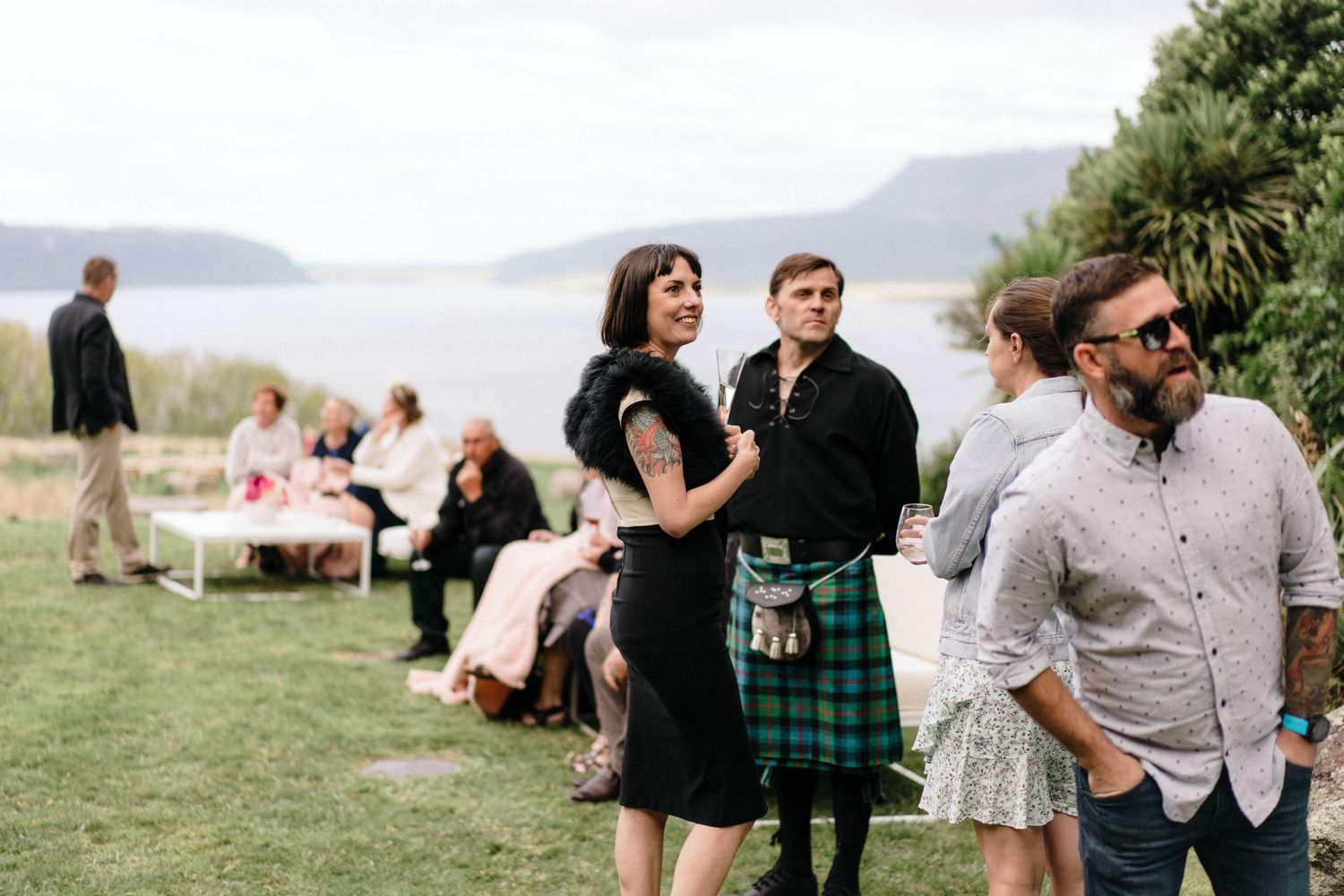 Guests mingle outdoors at a casual wedding reception with mountain views in the background.