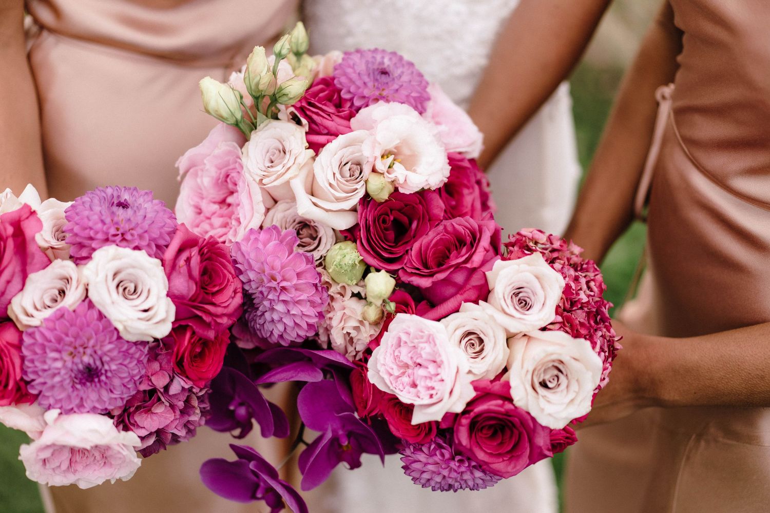 Close-up of stunning pink and purple wedding bouquets with roses and mixed flowers.