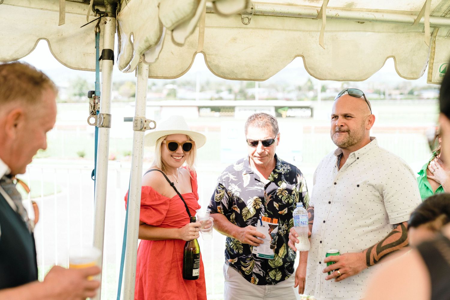 Group of people socializing under a white tent at an outdoor event.