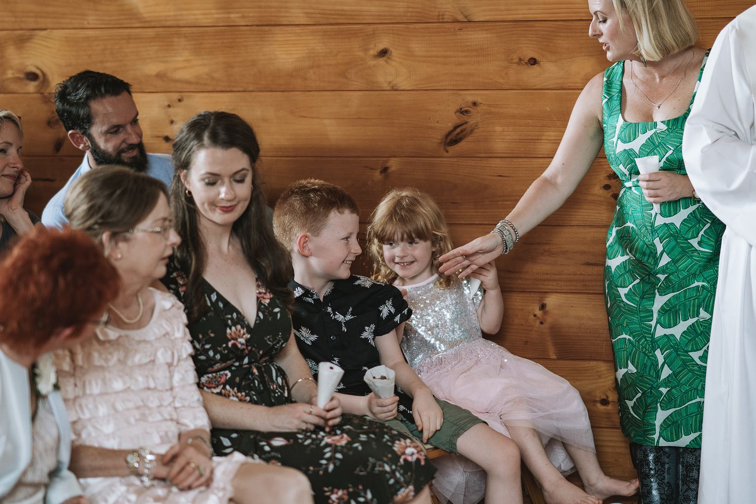 A group sits together on a wooden bench, sharing a joyful moment as they gather for a casual indoor occasion.