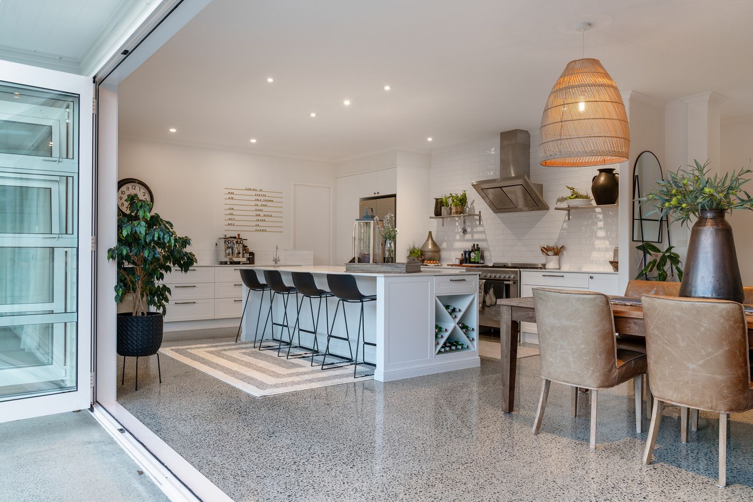Modern open concept kitchen with island, pendant lighting, and dining area with bi-fold doors.