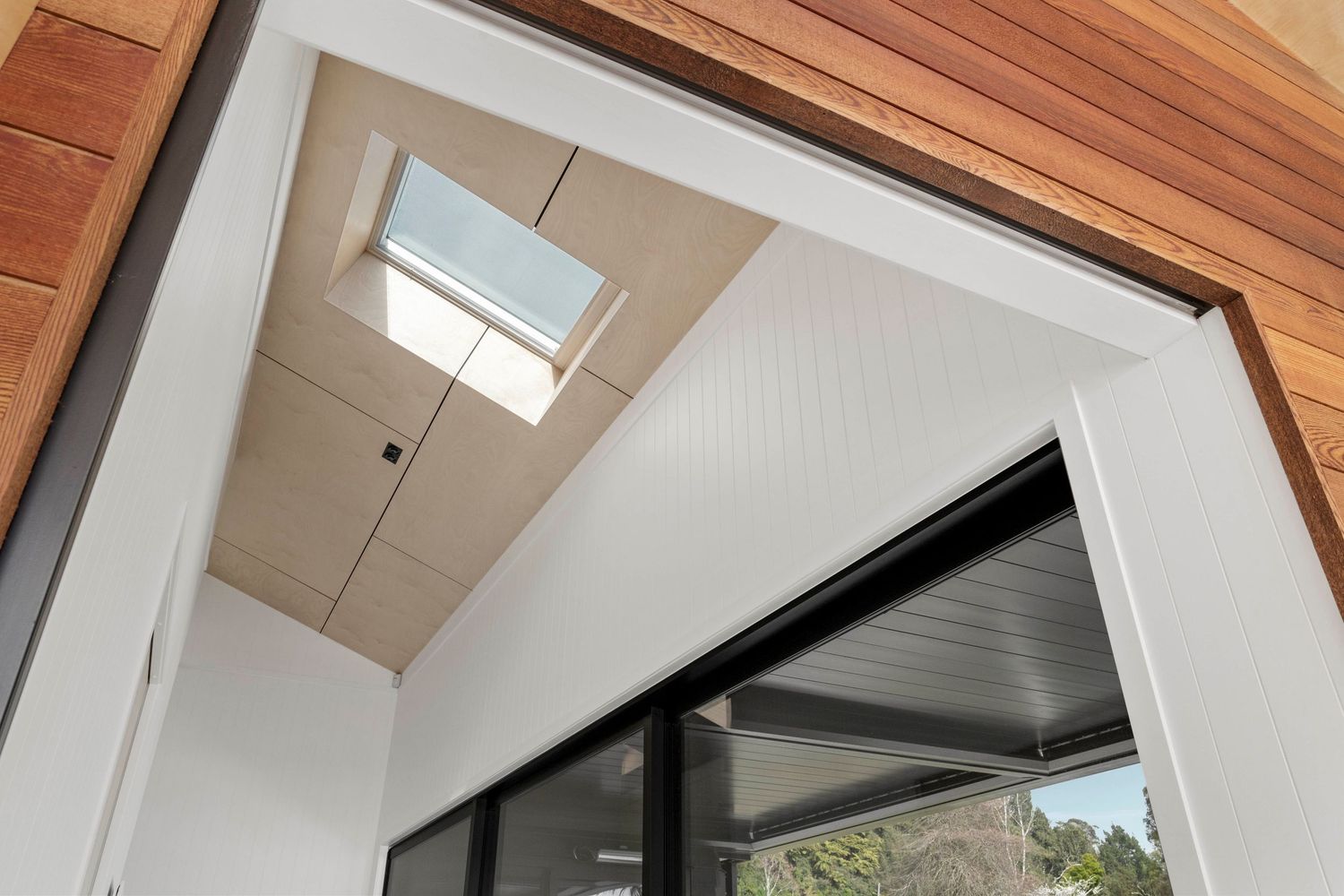Vaulted wood ceiling with skylights brightens a modern interior space featuring clean architectural lines.