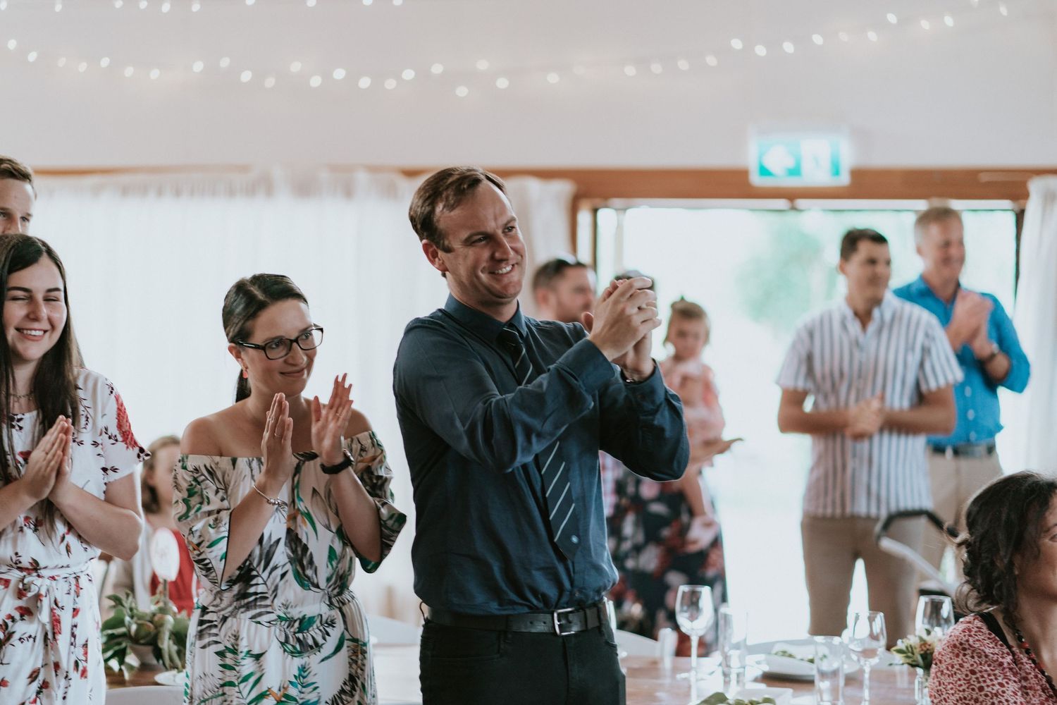 People dancing and socializing together at a lively indoor party with string lights overhead.