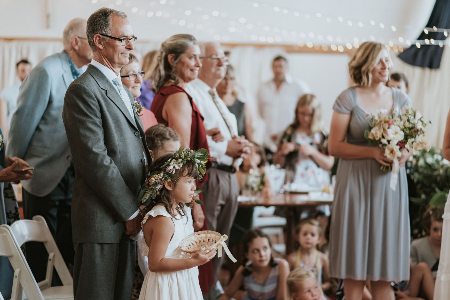 Wedding guests stand and applaud during an emotional reception celebration in an elegant white venue.