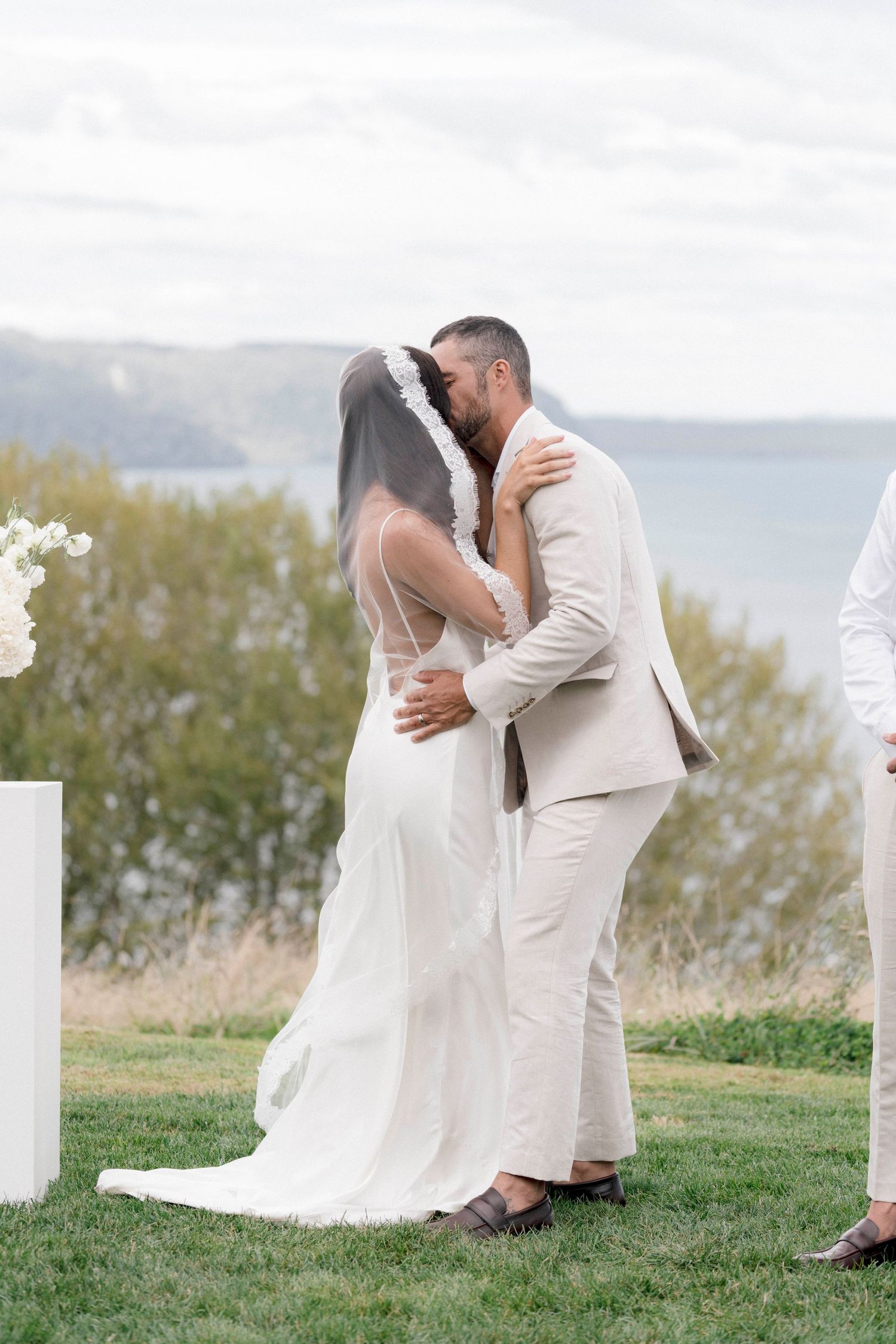 Newlyweds share their first kiss as husband and wife during outdoor ceremony with mountain backdrop.