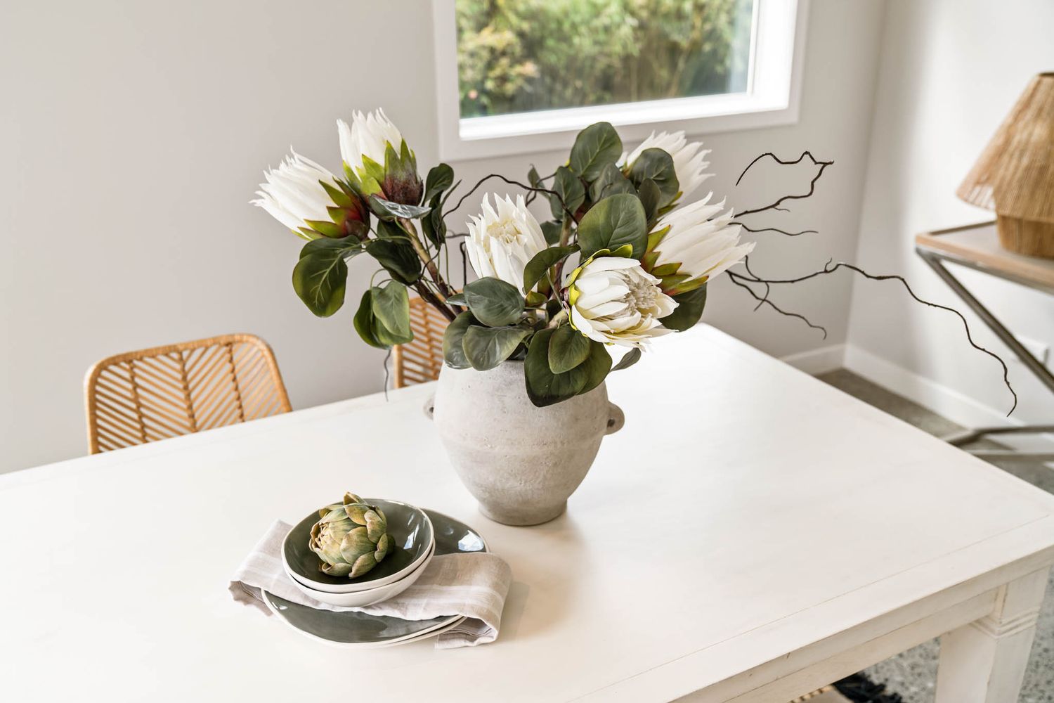 Modern white and gray kitchen island with marble countertop styled with decorative vases and floral arrangements.