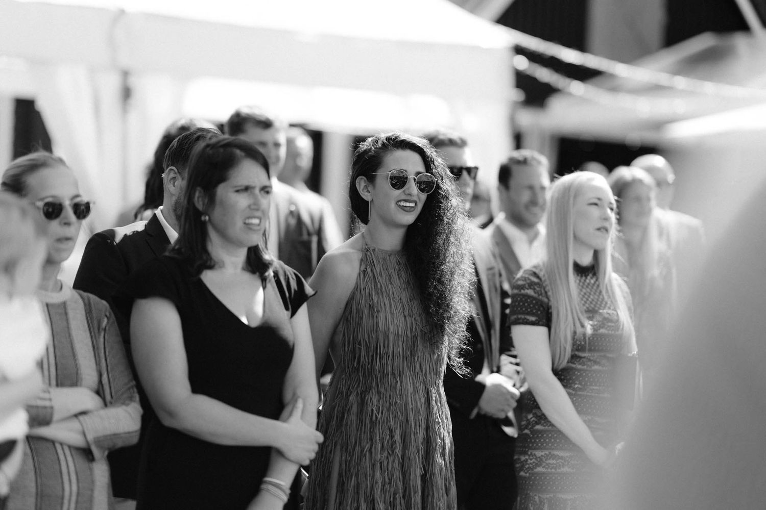 Black and white photo of wedding guests watching ceremony with mixed emotions and expressions.