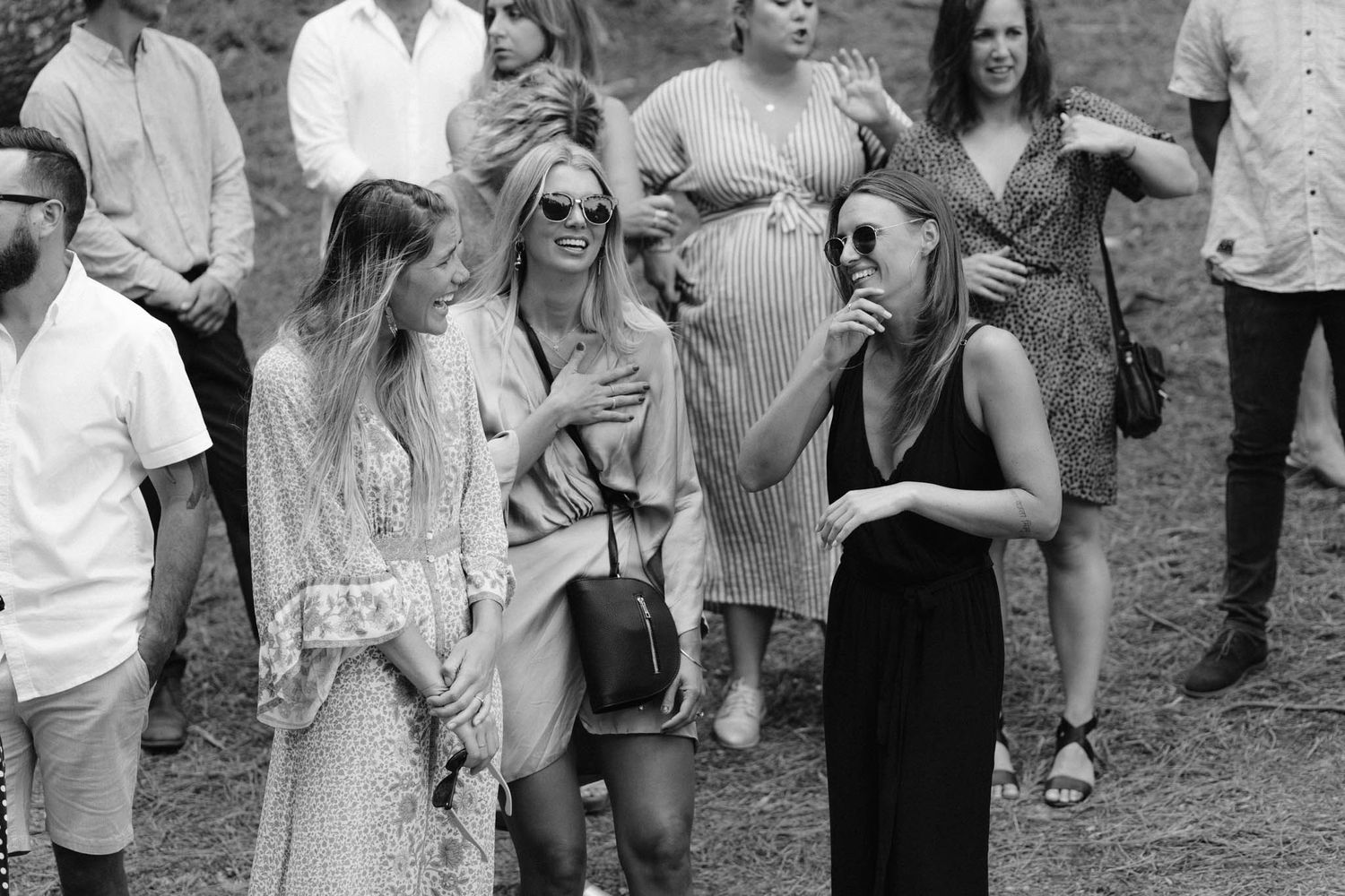 Group of wedding party attendees gathering outdoors in formal attire during a celebration event.