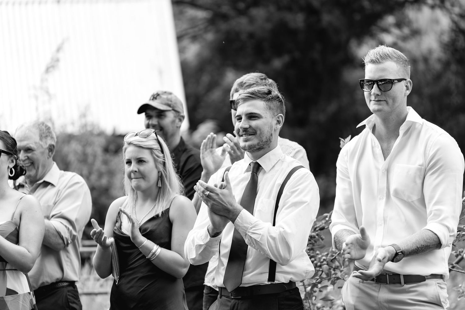 Black and white photo of wedding guests showing emotional reactions while watching ceremony outdoors.
