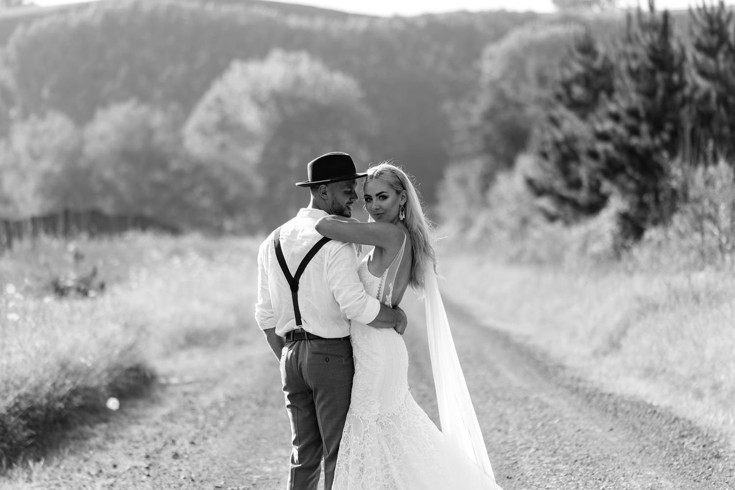 A series of black and white romantic photographs showing affectionate couples embracing on a countryside path.