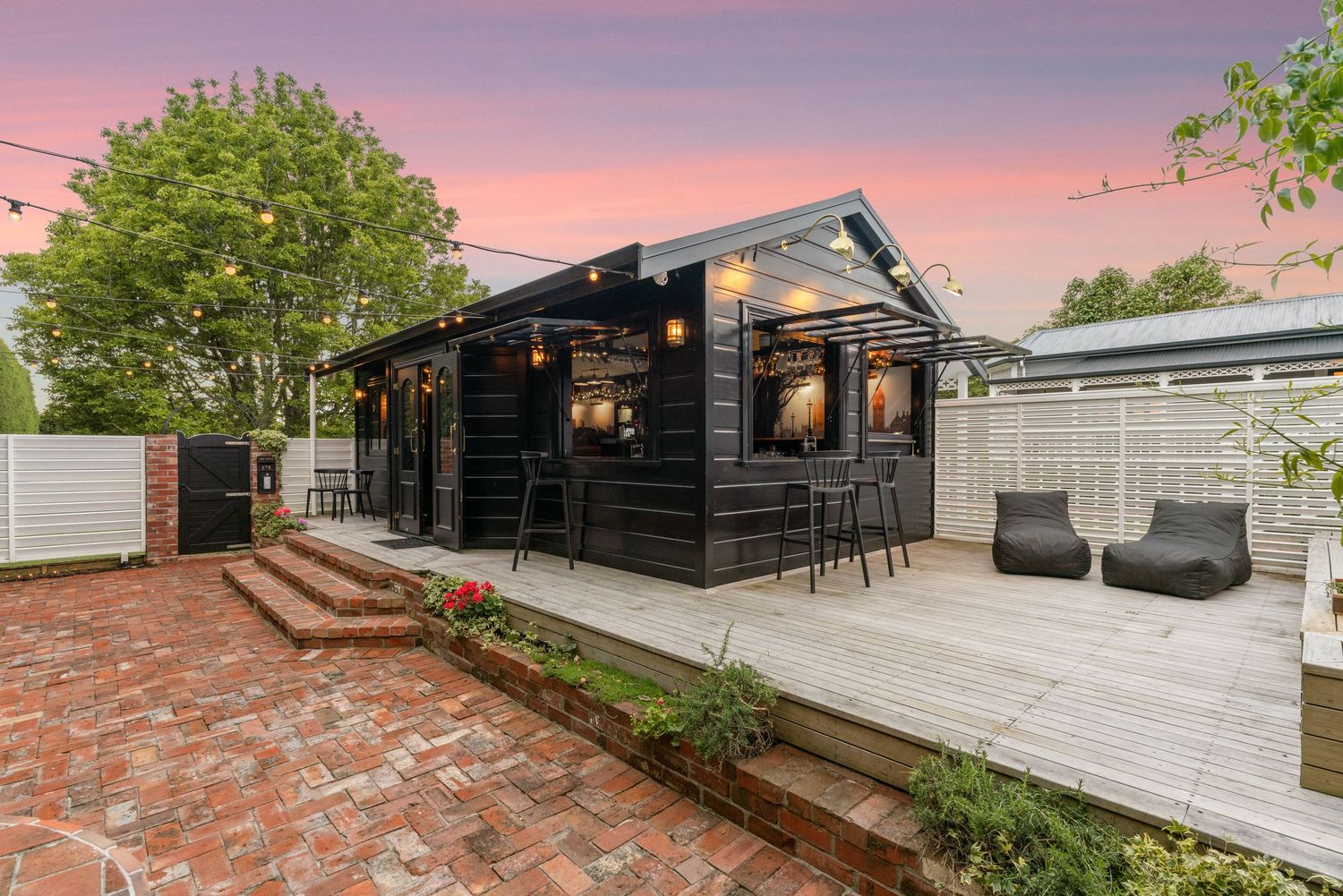 Outdoor entertainment area with string lights and modern seating during sunset.