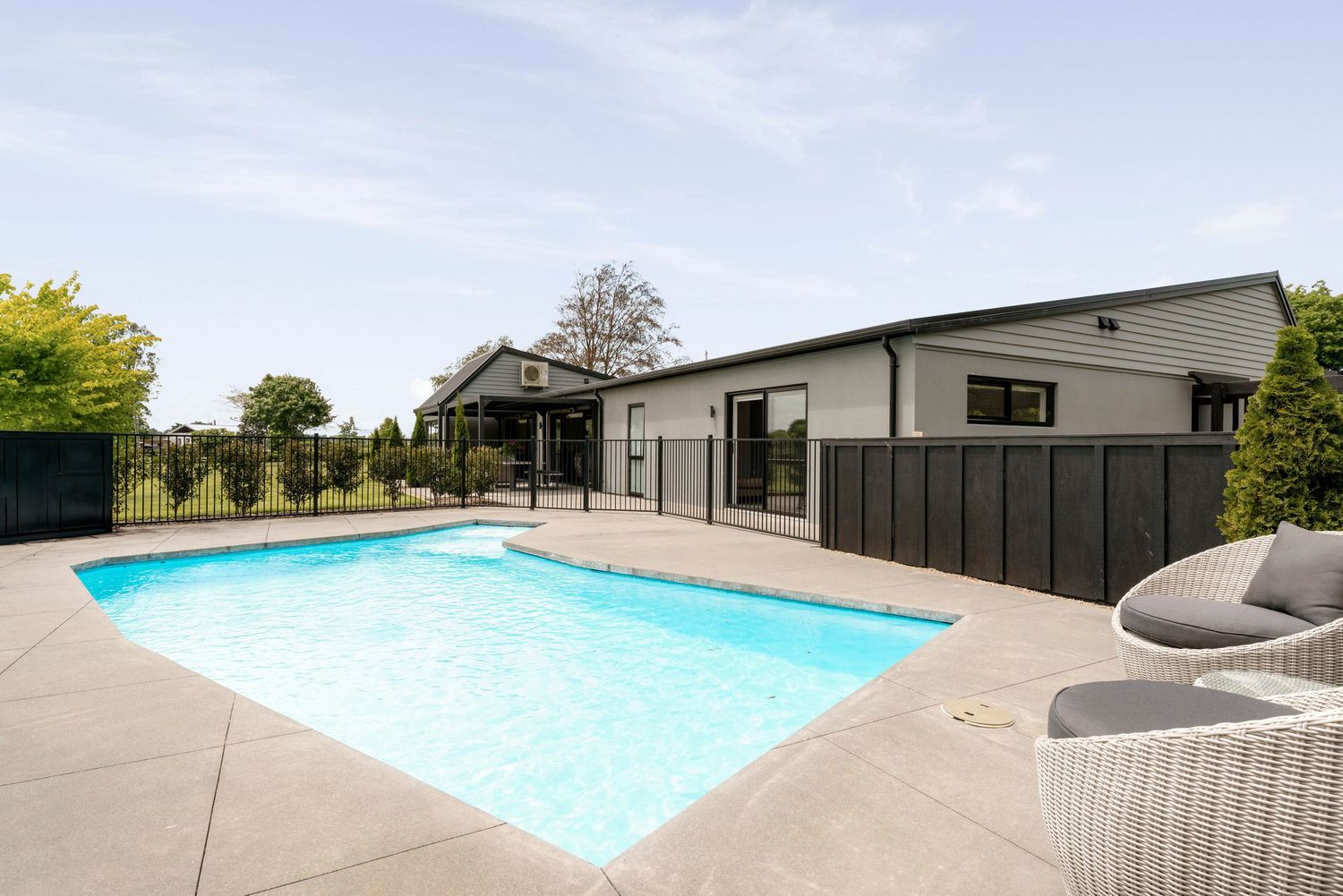 Sleek contemporary backyard with multiple swimming pools and minimalist deck design surrounded by greenery.