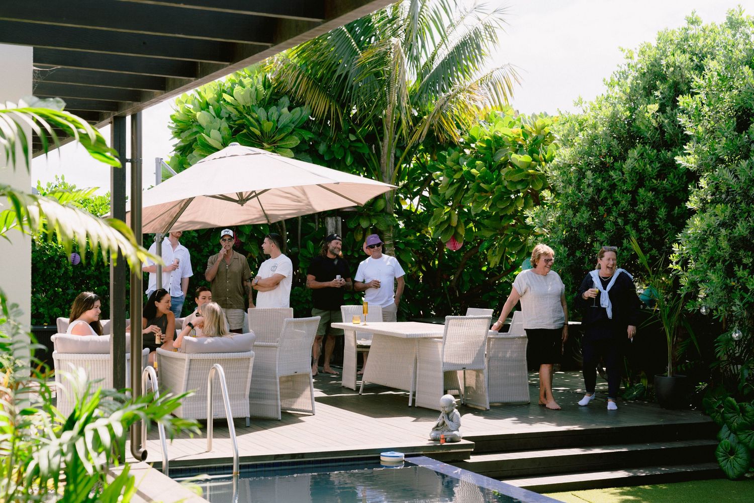 Elegant outdoor wedding venue setup with white umbrellas and chairs surrounded by lush tropical gardens and palm trees.