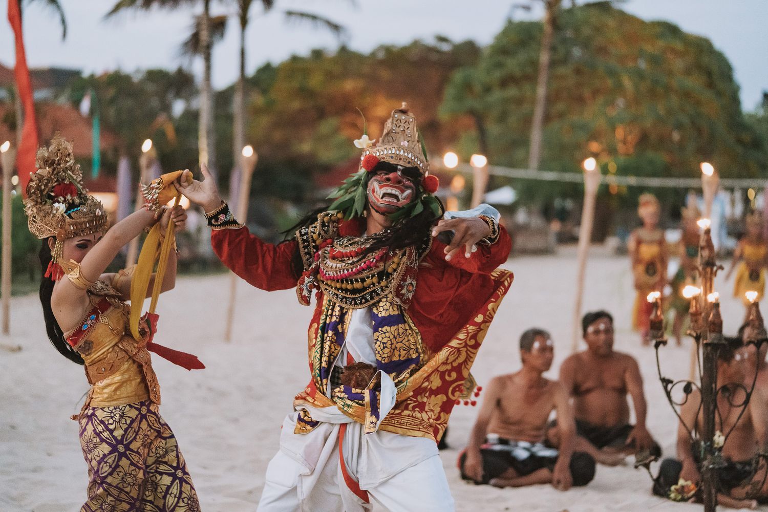 Traditional Balinese dancers perform in colorful costumes during a beachside wedding ceremony.