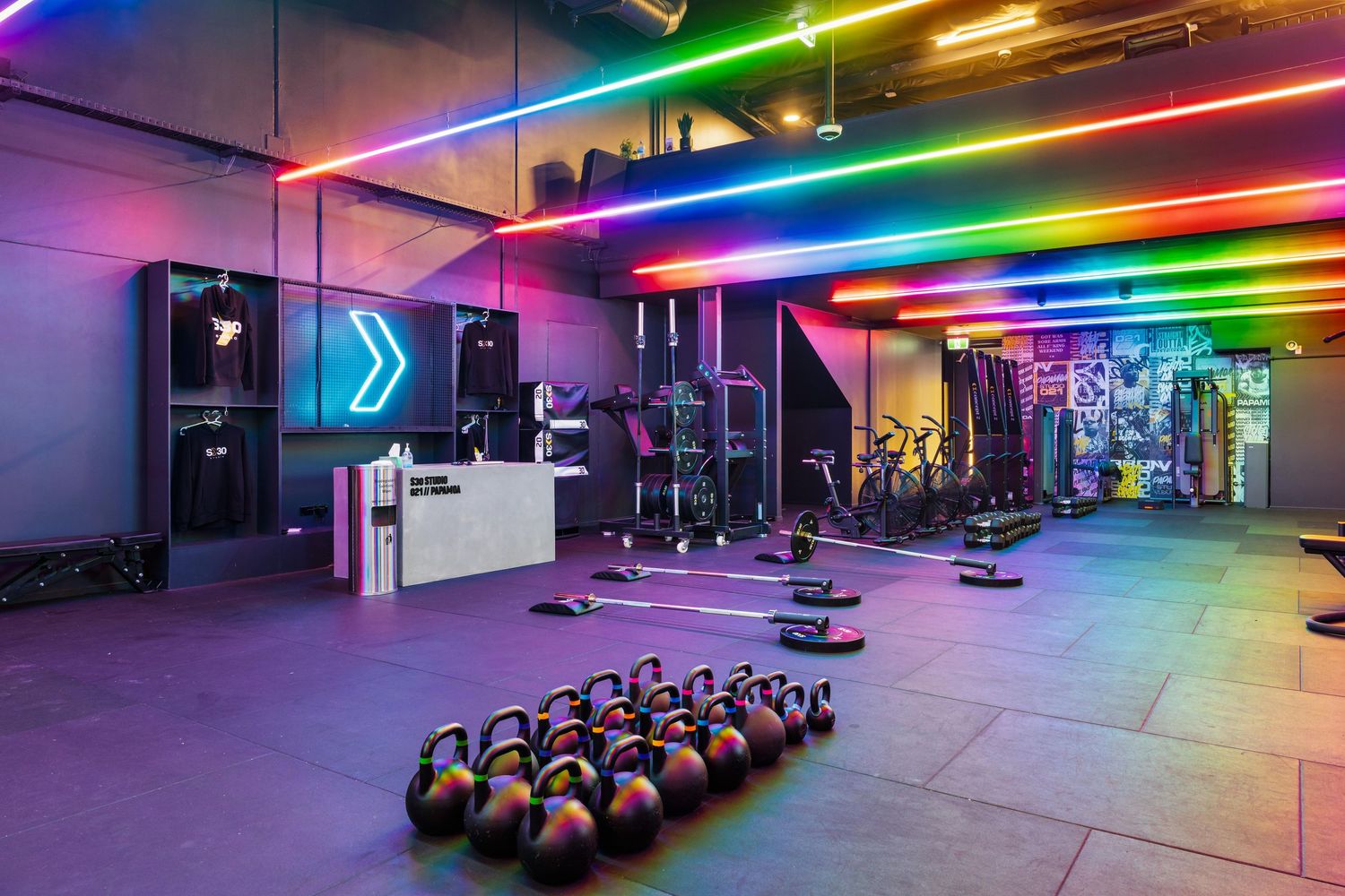 Rainbow LED lighting illuminates a modern gym space with fitness equipment.
