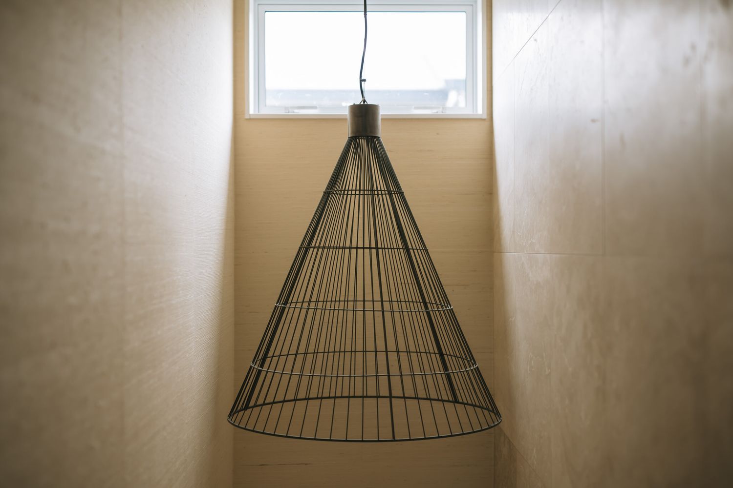 A sequence of photos showing an inverted wire lampshade mounted to a ceiling in different stages of assembly.
