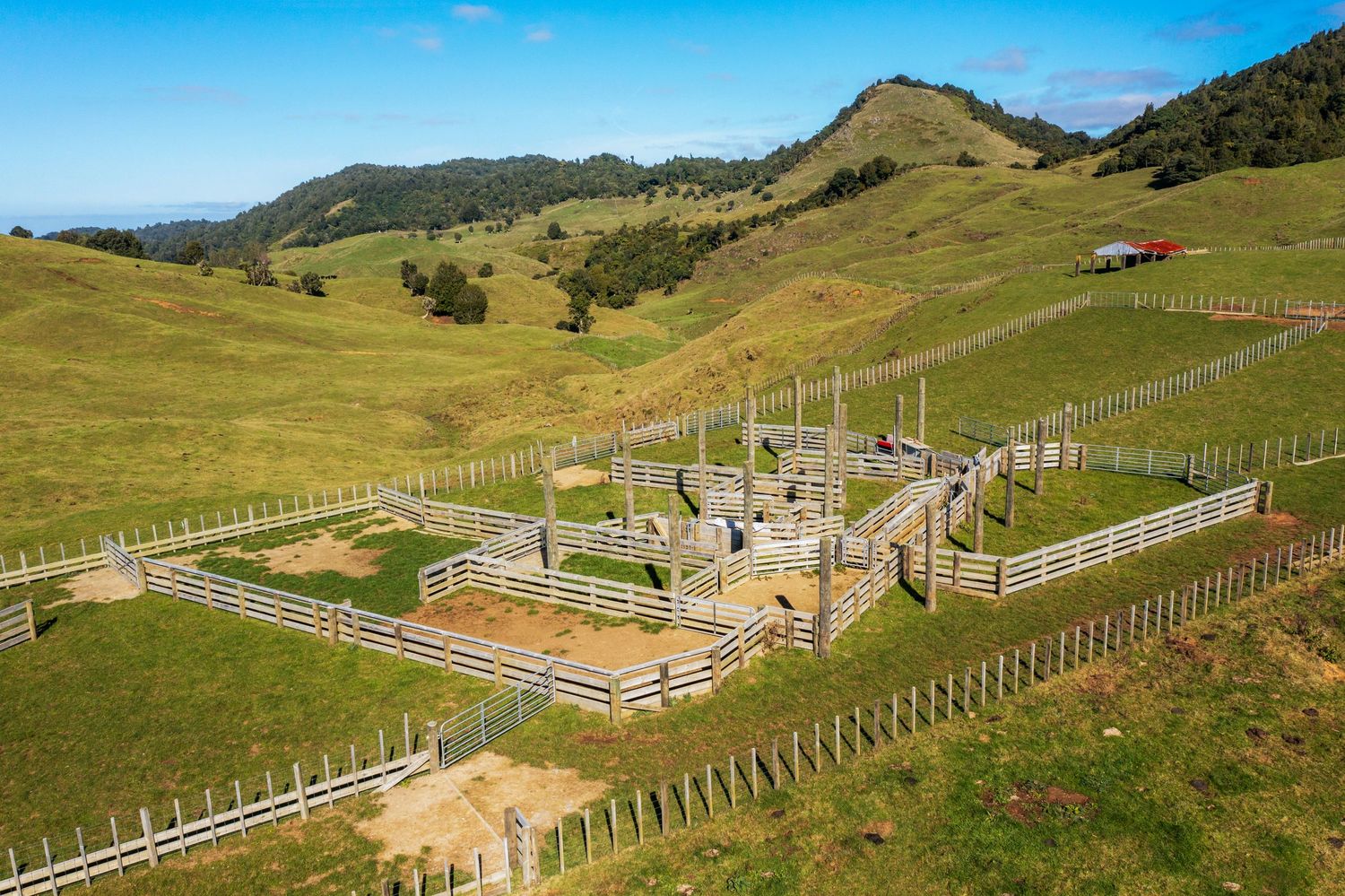 Wooden fence lines and paddocks stretch across rolling green hills on a rural farm property.