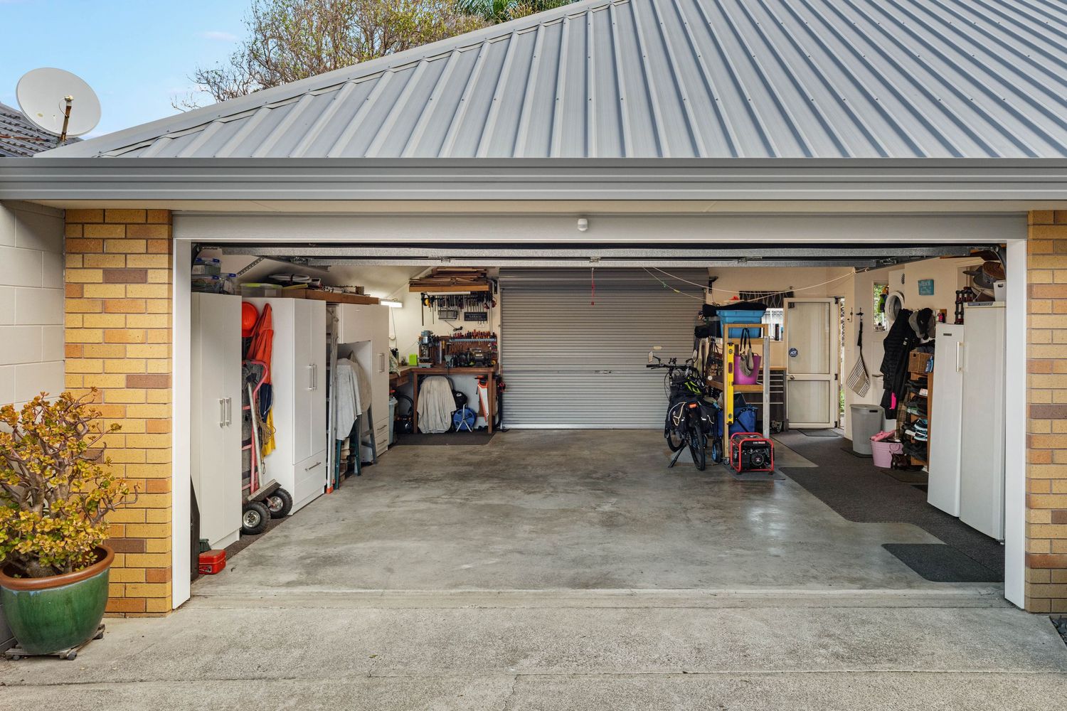 Organized residential garage interior with sports equipment and storage shelves along brick exterior walls.