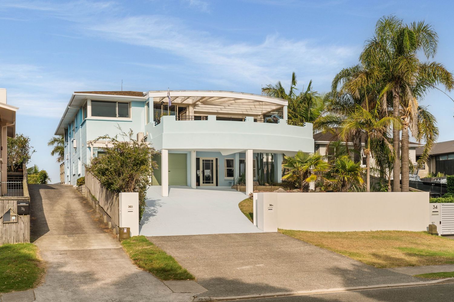 Modern two-story white coastal home with clean lines and palm trees in the front yard.