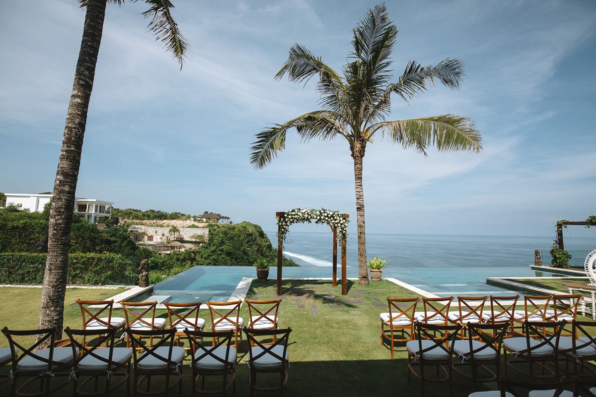 A scenic oceanfront resort view with palm trees and wooden railings overlooking the tropical beach landscape.