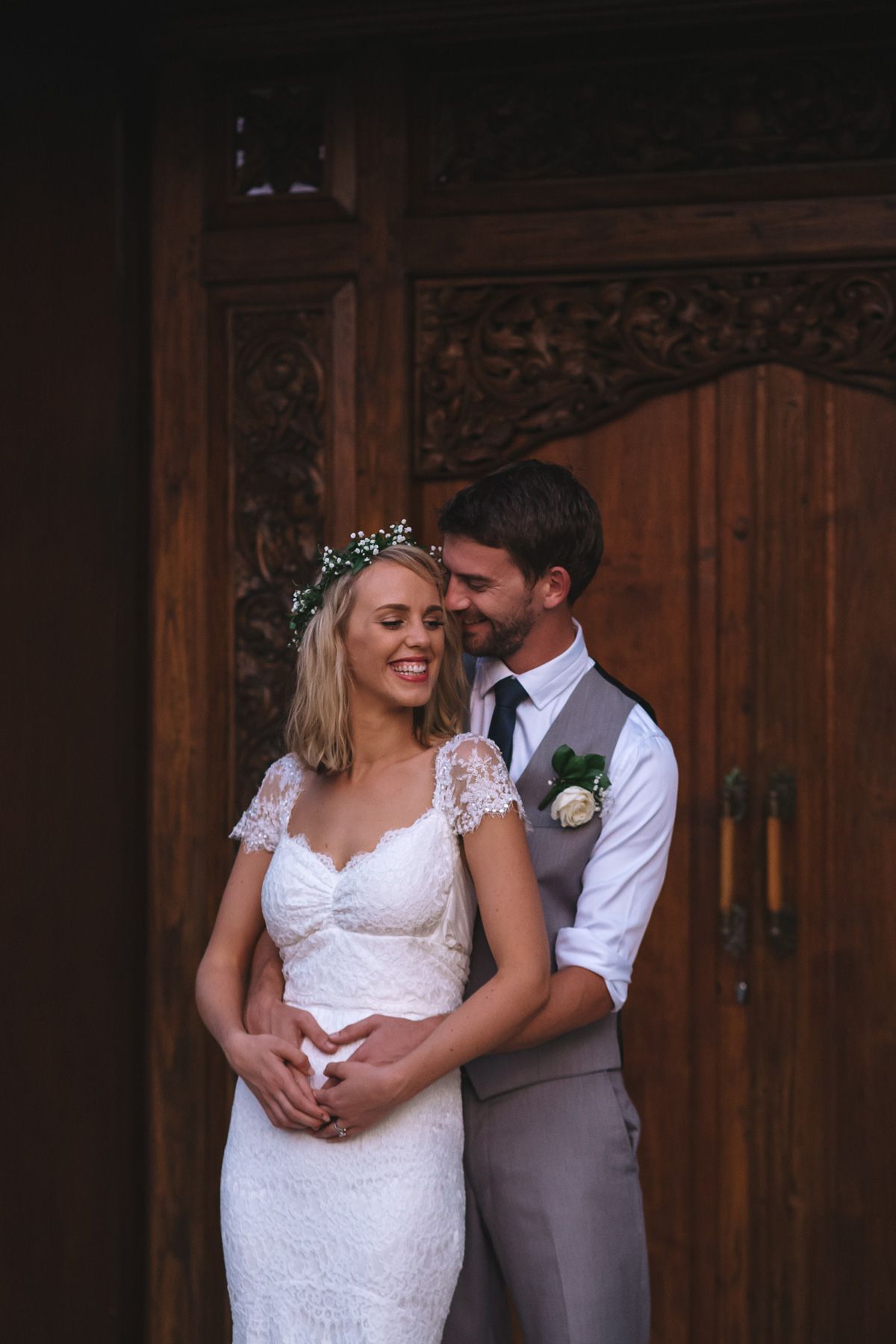 A couple shares an intimate moment in front of ornate wooden doors.