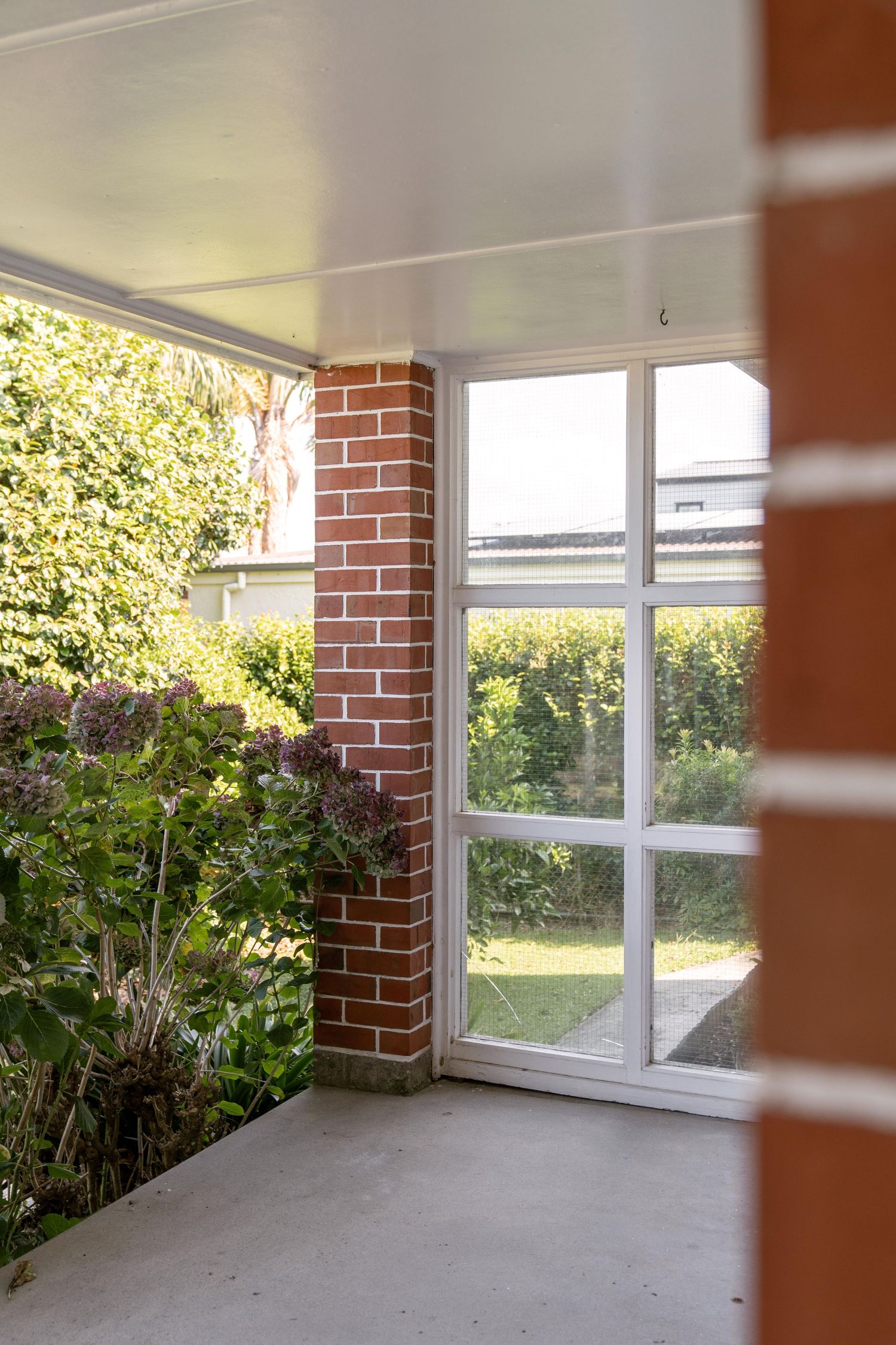 Bright sunroom with brick columns and large windows overlooking a garden view.