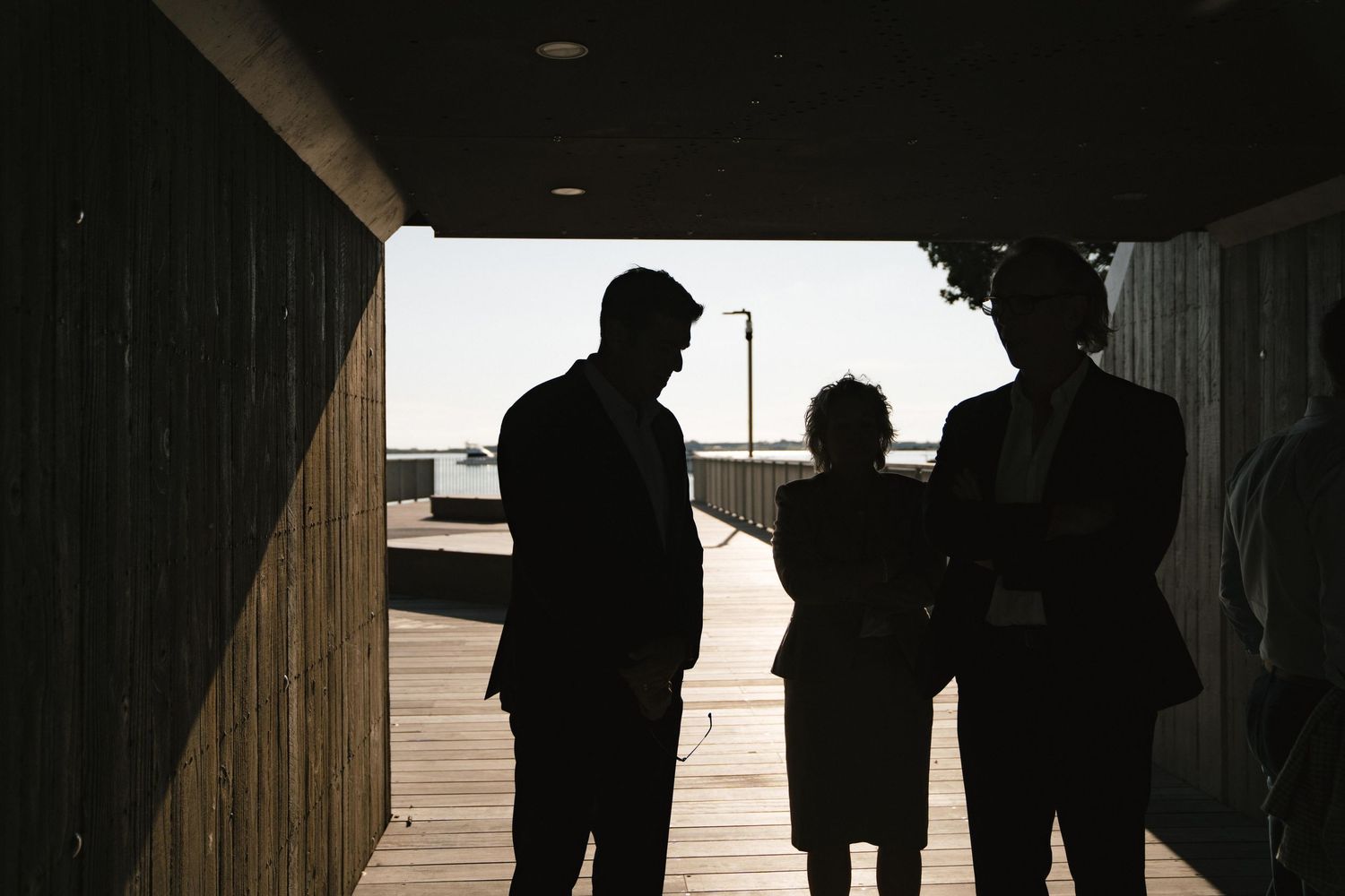 Silhouettes of business professionals conversing in a dark office corridor.