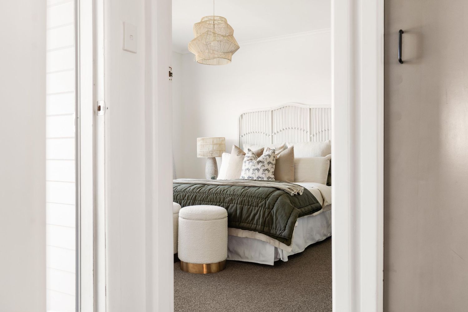 Minimalist bedroom interior with white bedding, gray throw, and modern pendant light.