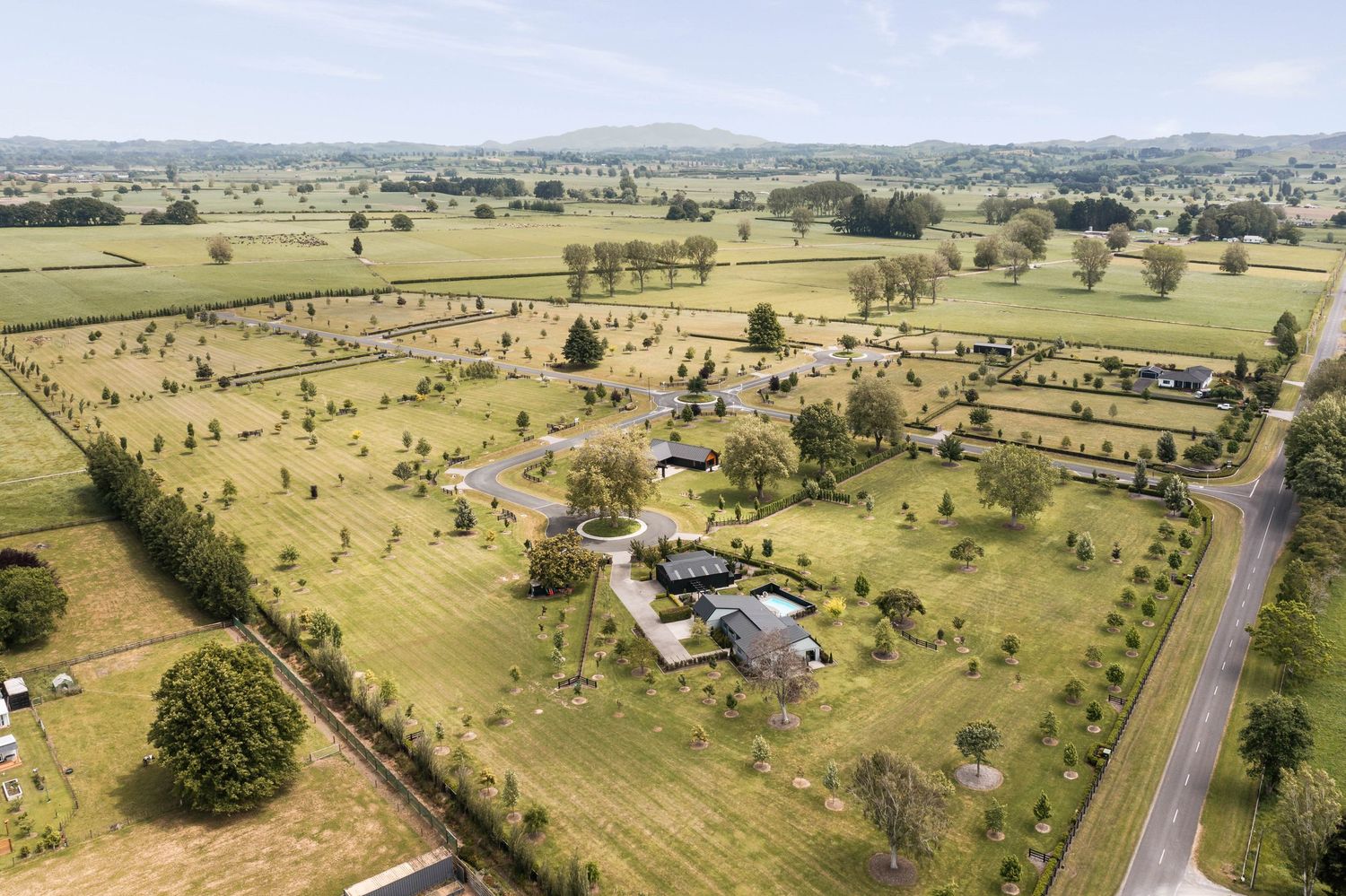 Aerial panoramic view of rural countryside with scattered homes, fenced pastures and winding roads.