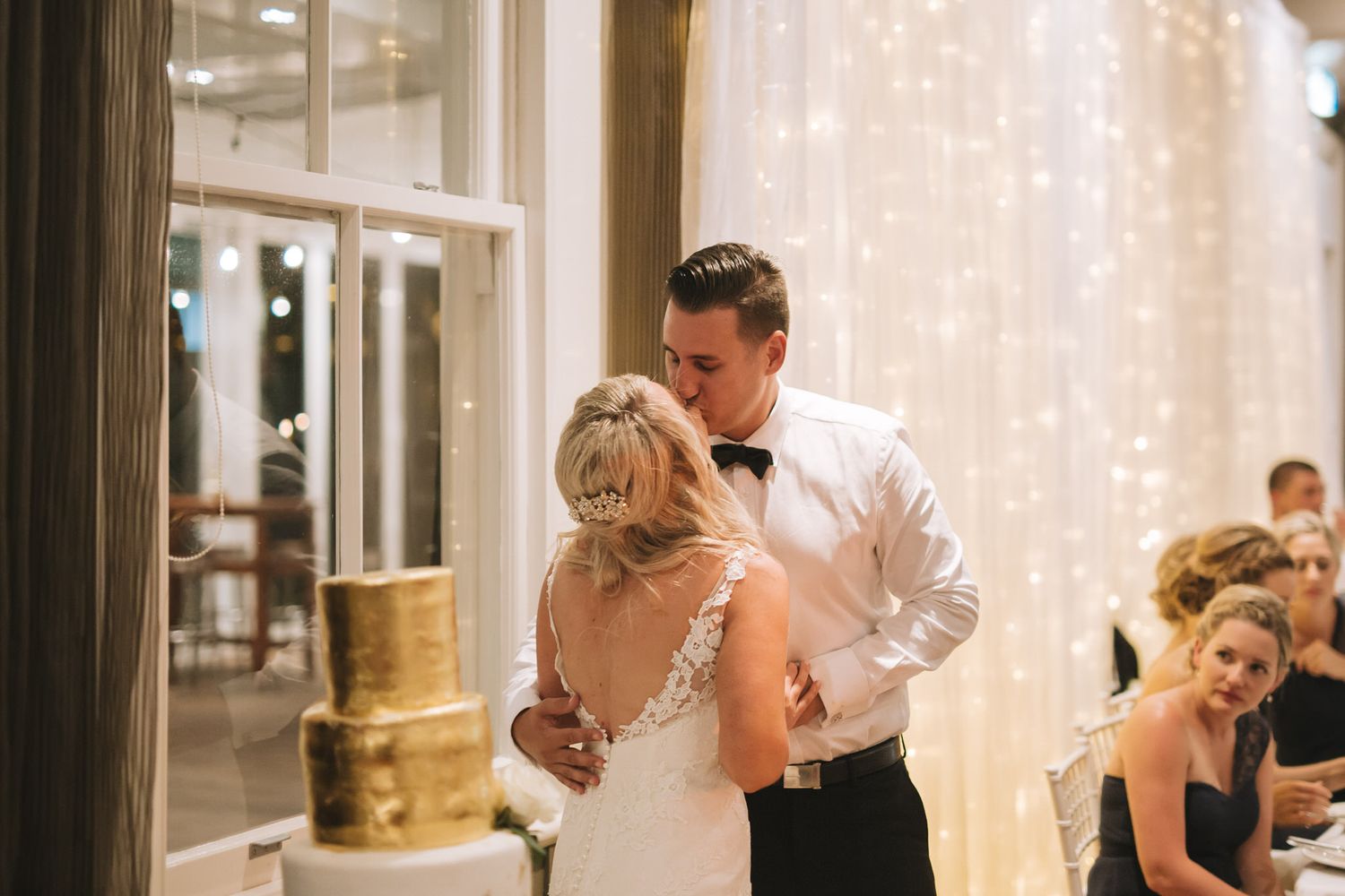 A group of people enjoying a special moment on a dance floor with soft lighting and decor in the background.