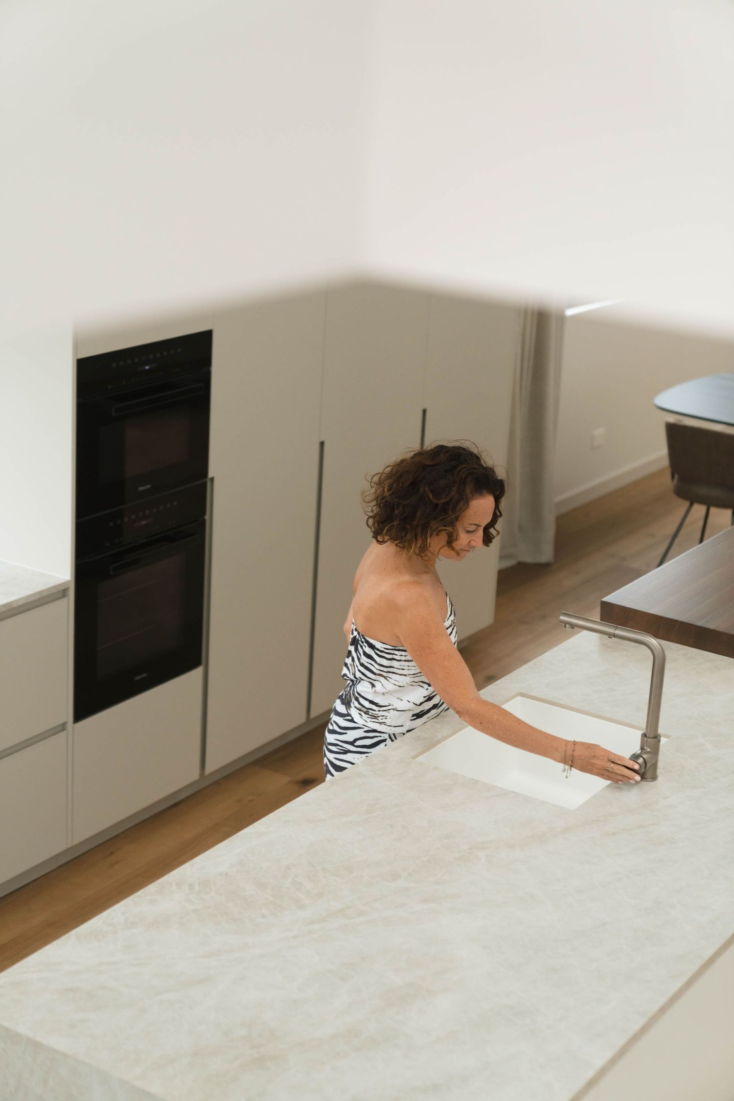 Person wearing zebra print examining sleek modern kitchen cabinetry.