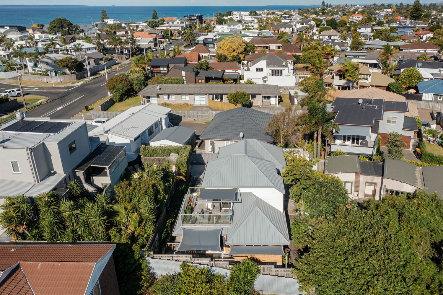 Aerial panoramic view of oceanfront homes and beach houses along the California coastline on a sunny day.