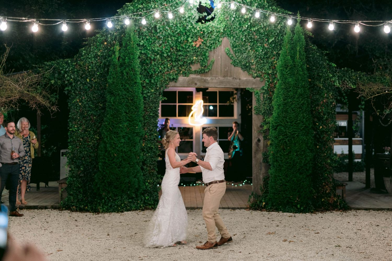Evening wedding reception with string lights illuminating ivy-covered walls.