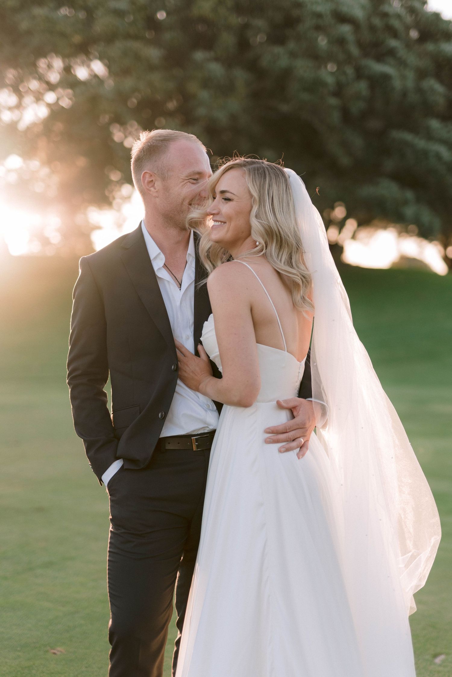 Intimate sunset wedding portraits with couple sharing tender moments on a grassy lawn.