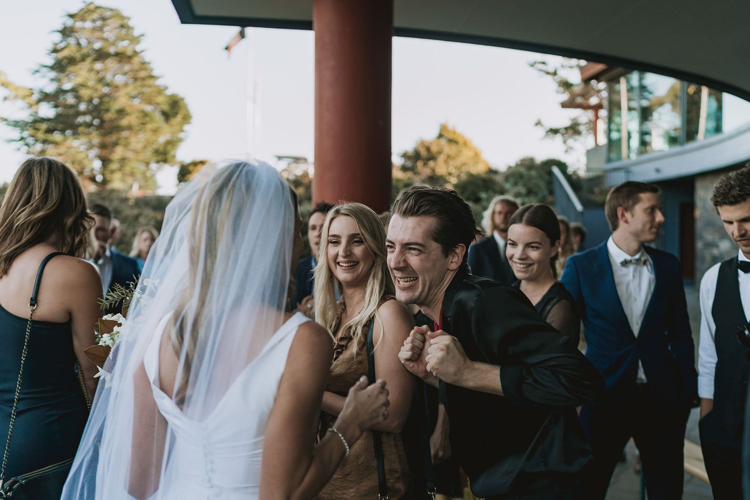 Wedding party guests sharing candid laughs and joyful moments during an outdoor celebration.