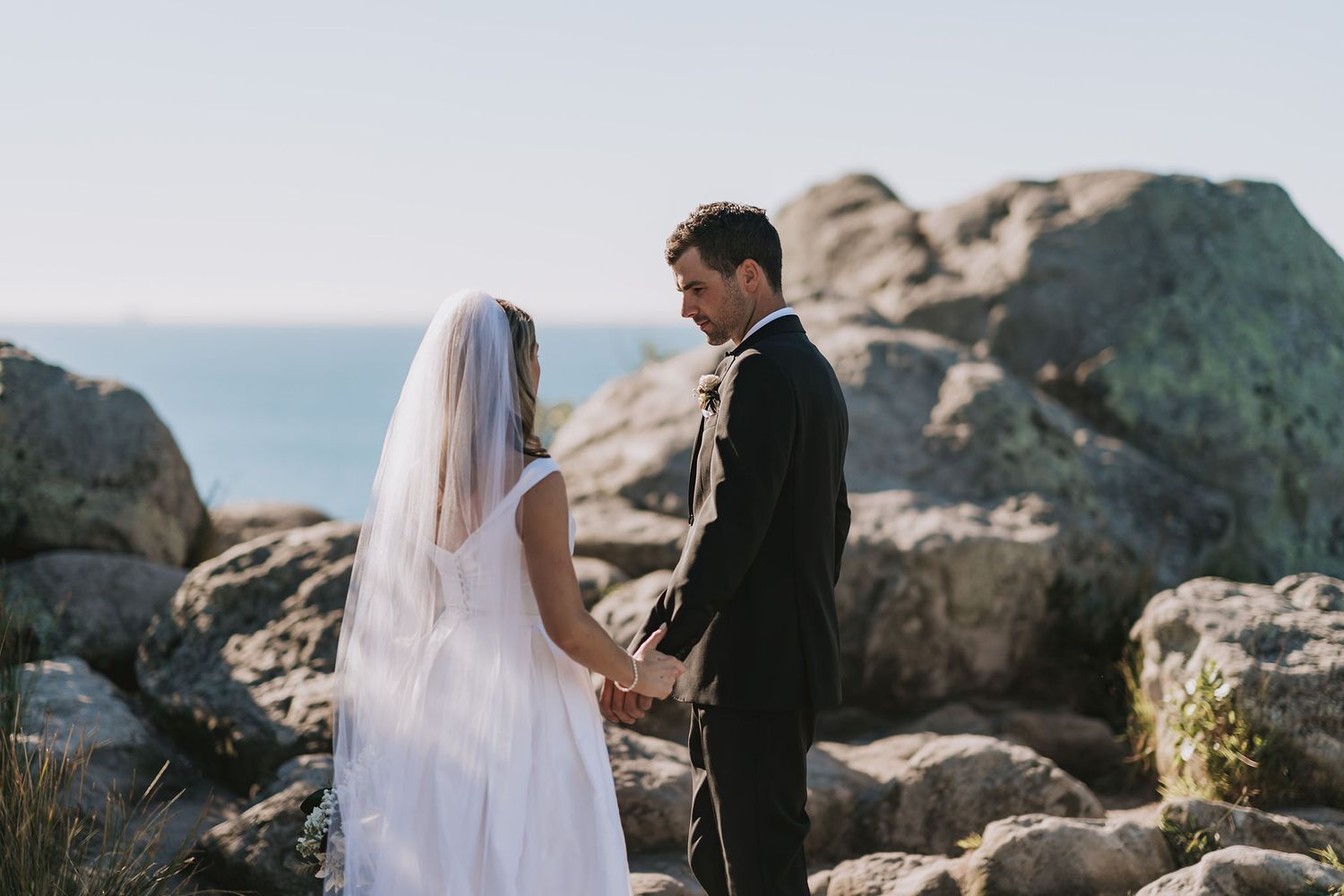 A couple stands together on rocky mountain terrain during their elopement wedding ceremony with scenic views.