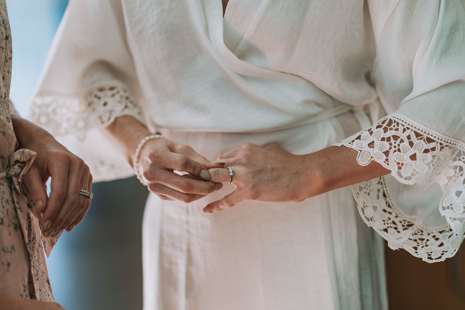 A close-up view of a delicate white lace wedding dress sleeve details against a light background.