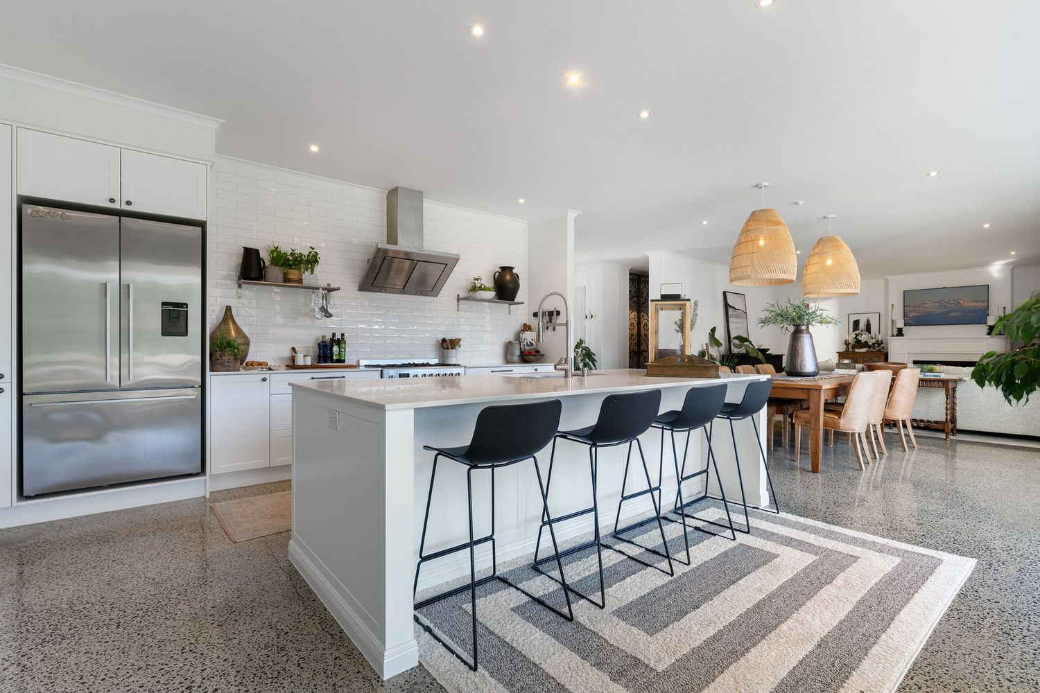 Spacious modern kitchen with white cabinetry and grey flooring extending into living area.