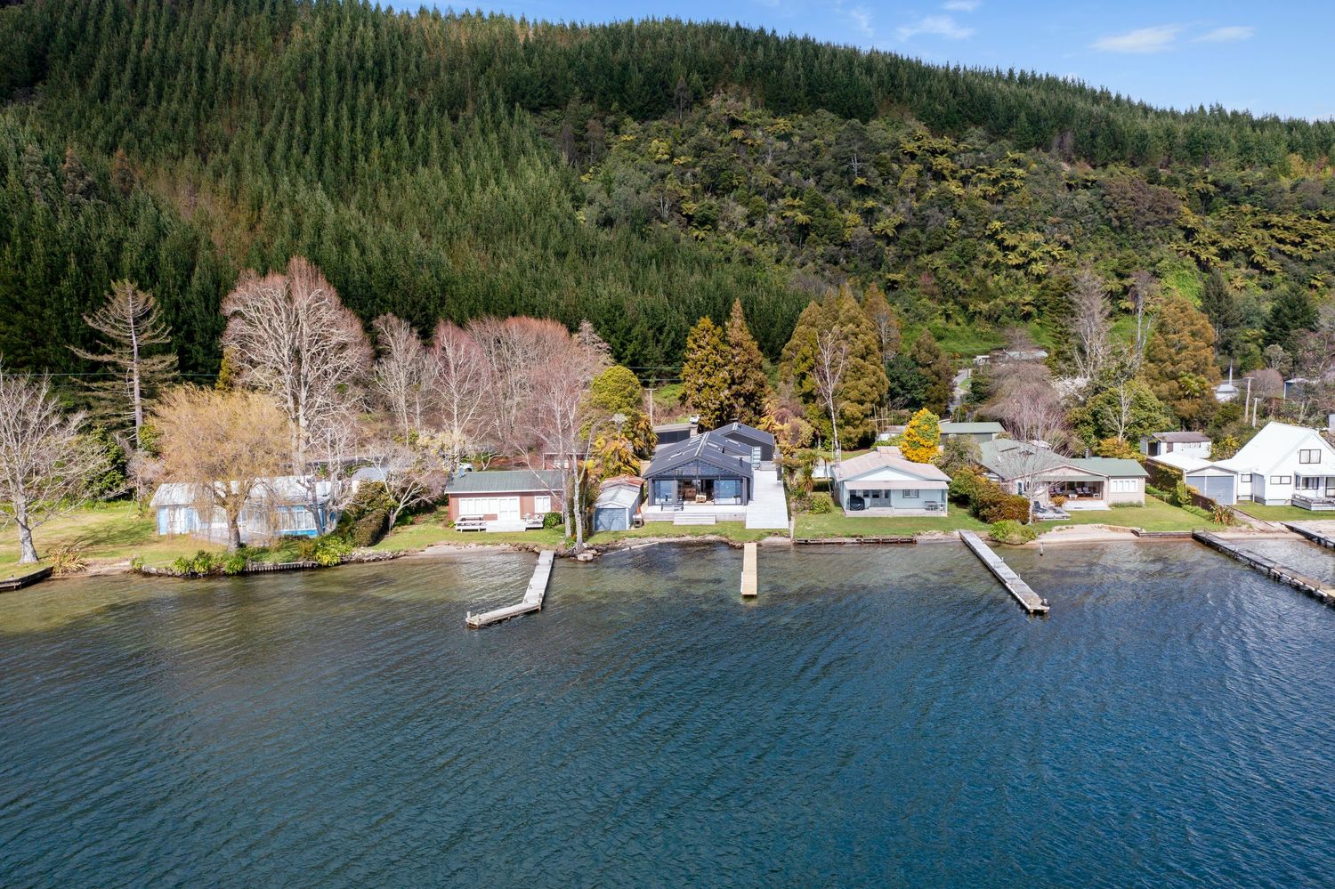 Aerial view of waterfront homes with private docks along a forested shoreline during autumn.