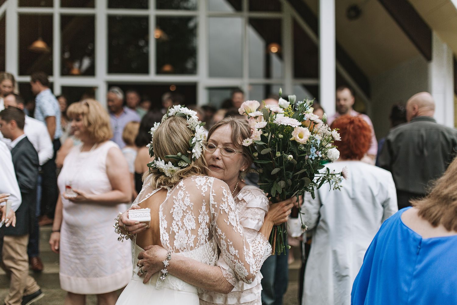 Elegant wedding guests mingle and socialize during an outdoor cocktail reception at a rustic venue.