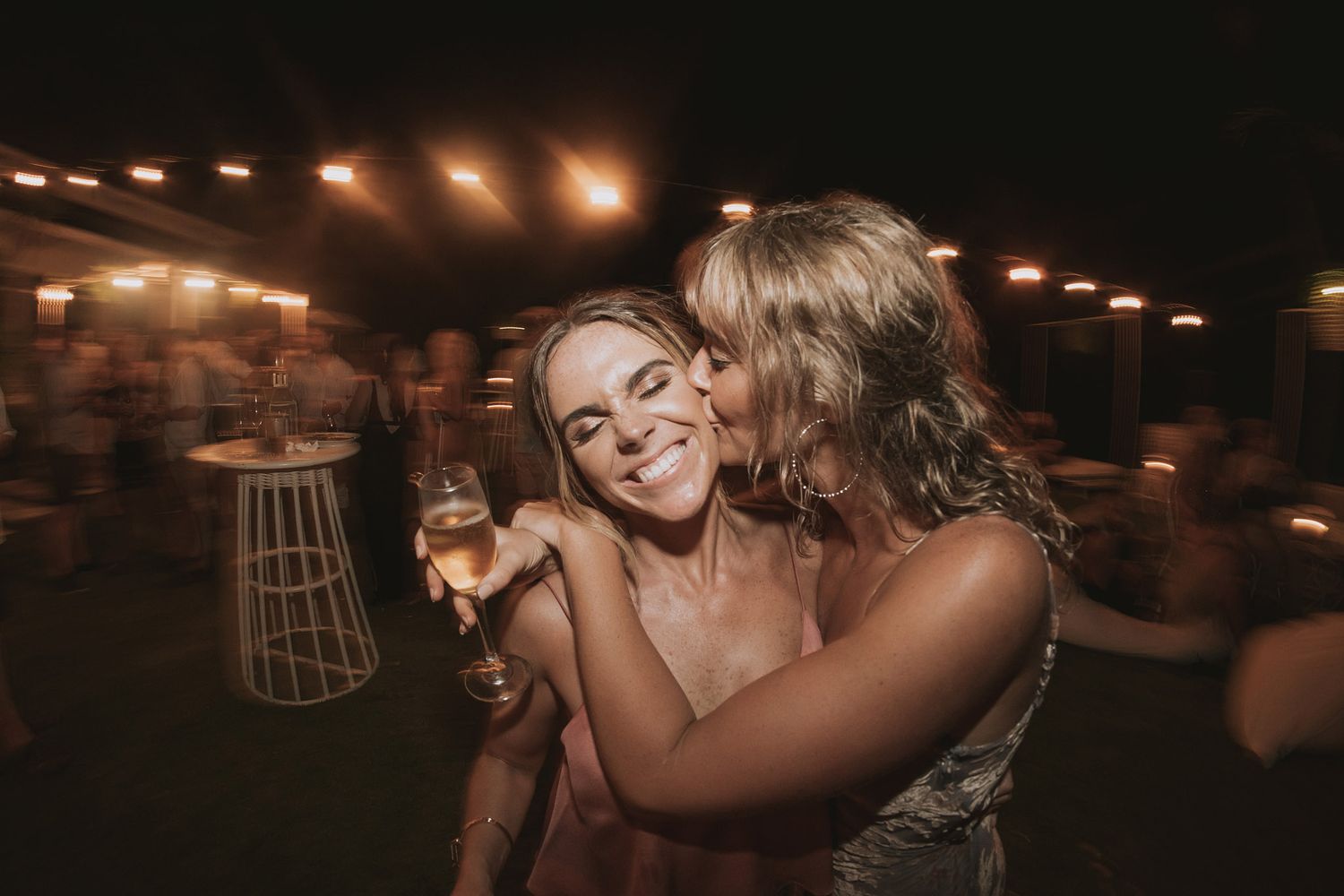 Dance party scene at wedding reception with warm lighting and celebrating guests.
