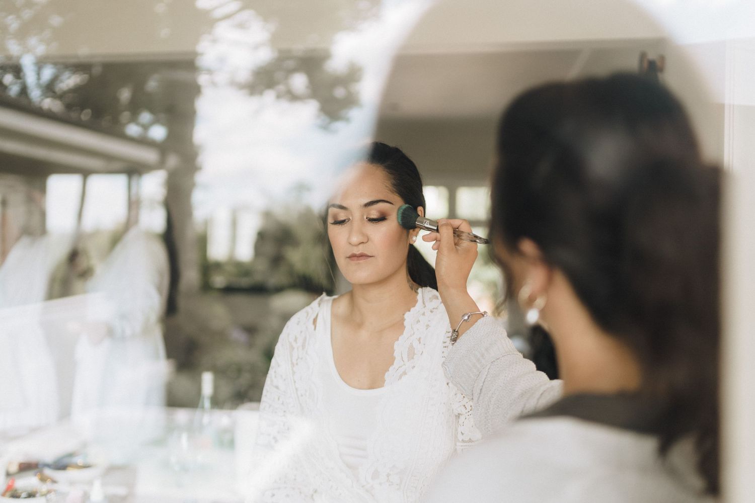 Wedding preparation scene with makeup application in soft natural lighting.