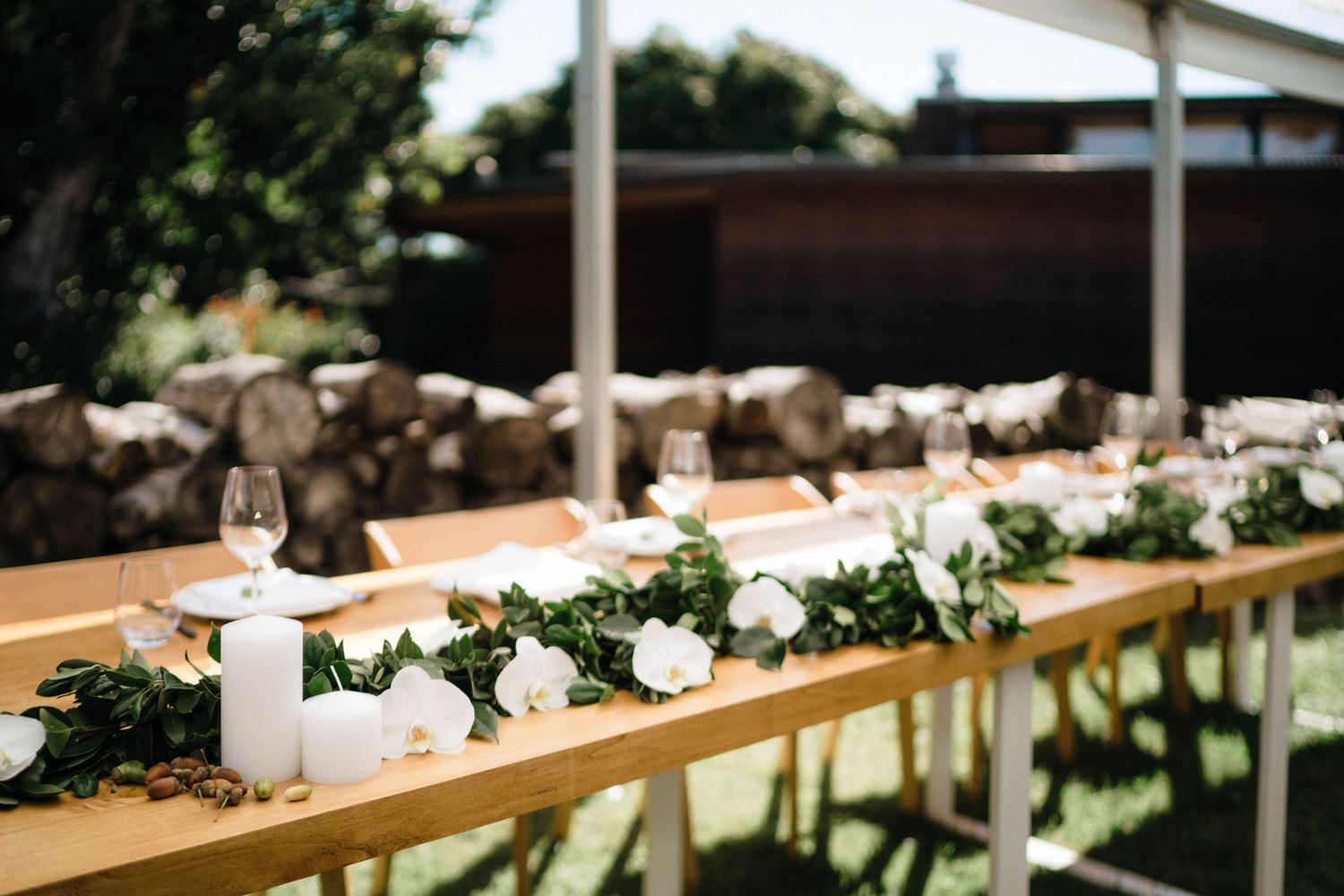Long wooden banquet table decorated with white floral garland and greenery centerpieces.
